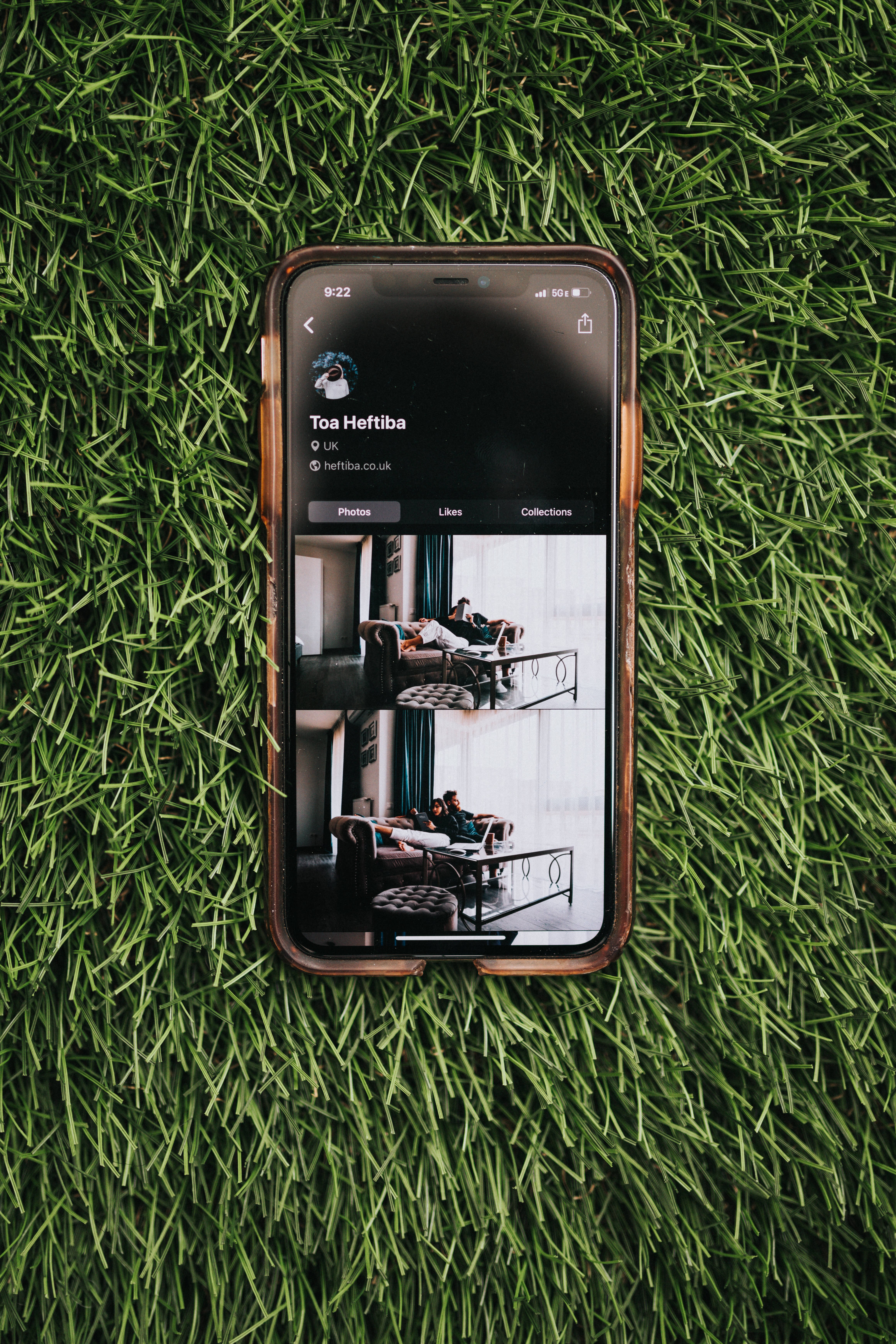 iPhone iOS置於草地上 壁紙 — 一部顯示Instagram個人資料的智能手機放在充滿活力的綠色人造草上。