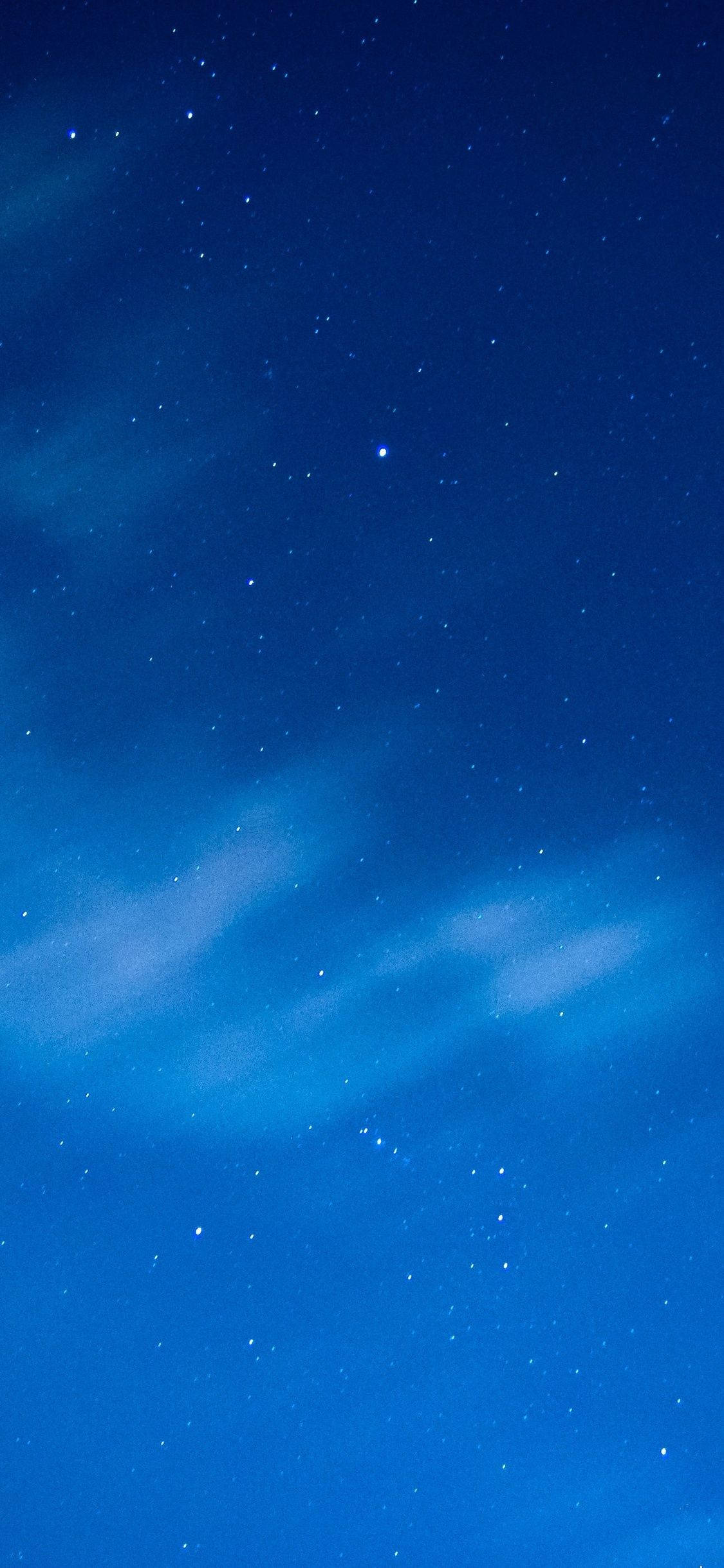 夜空藍色 iPhone 壁紙 — 深藍色的夜空佈滿閃爍的星星和飄過天際的縷縷薄雲。
