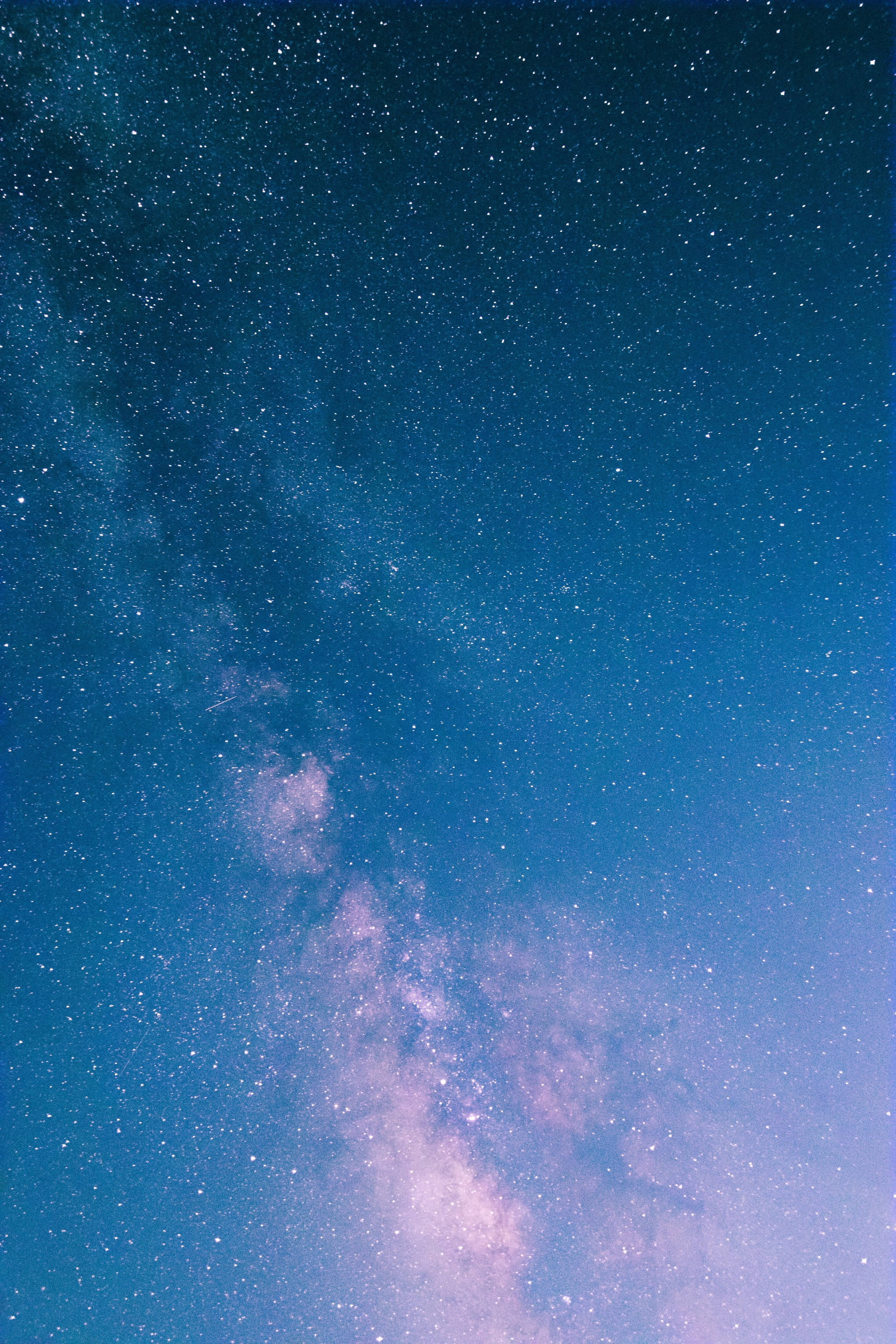 柔霧藍調iPhone主題 壁紙 — 令人嘆為觀止的銀河系景觀，在繁星點點的夜空中閃耀著粉紅色和藍色的色調。