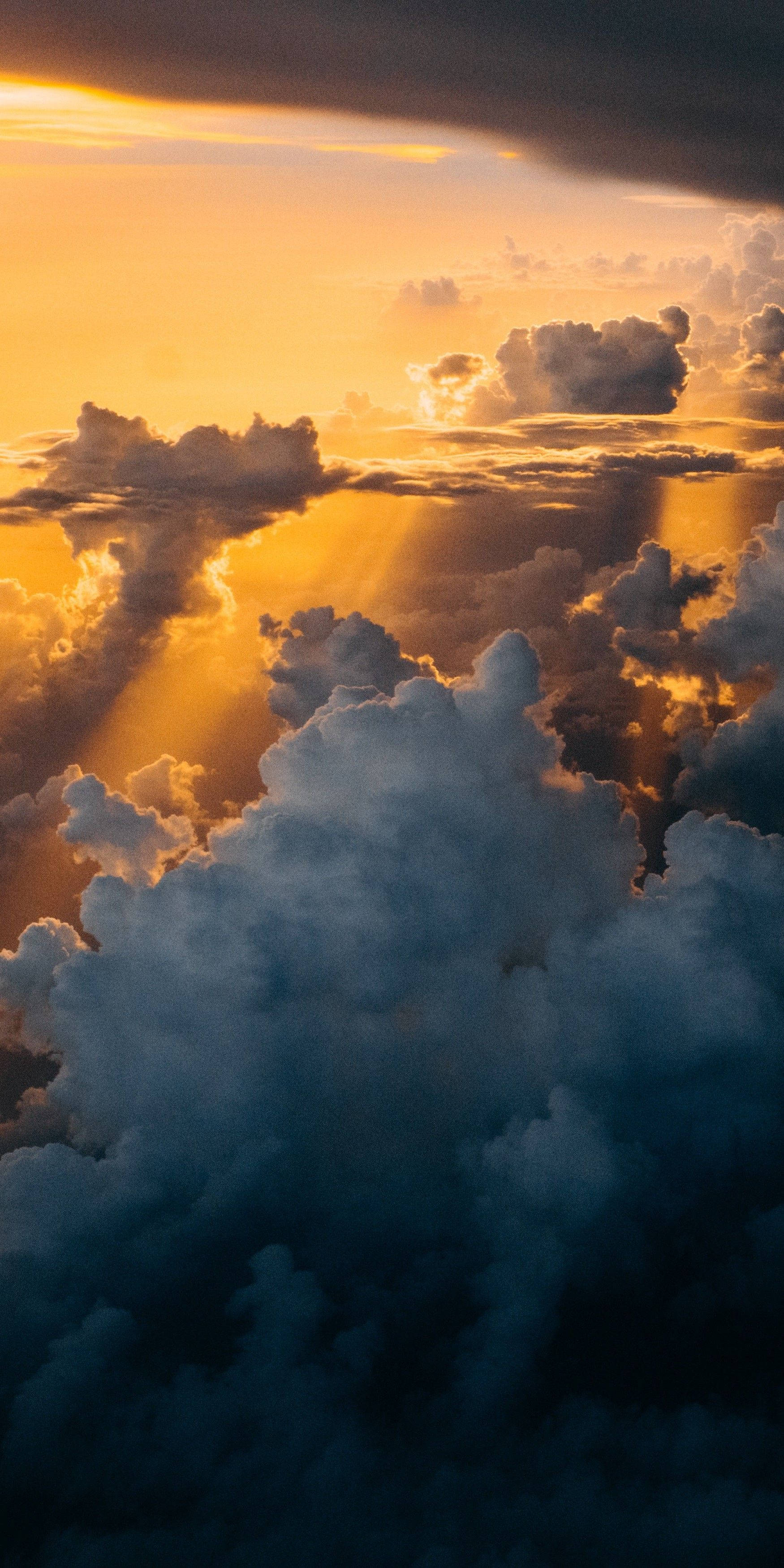 iPhone X 展示驚人的 4K HDR 解析度 壁紙 — 金色陽光穿透戲劇性的雲層，呈現令人驚嘆的日落天空。