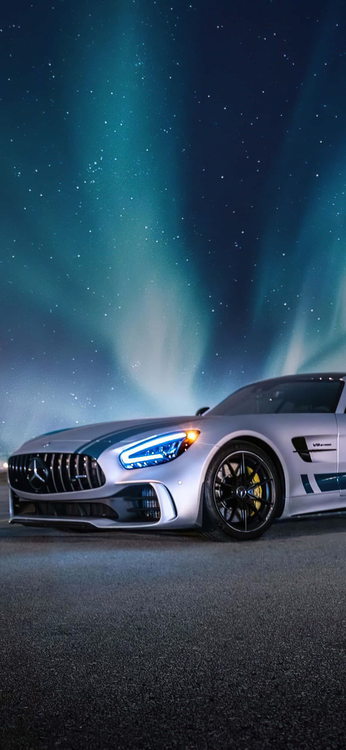 iPhone X AMG GT-R 背景：AMG GT 與極光交織 壁紙 — 時尚的銀色跑車在充滿活力的綠色極光下閃耀，映襯著星空夜空。
