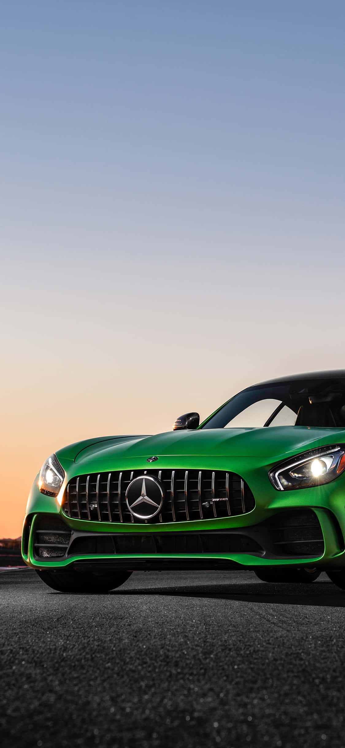 iPhone X AMG GT-R 背景綠色 AMG GT R 壁紙 — 一輛充滿活力的綠色Mercedes-AMG GT跑車在柔和嘅日落天空下喺瀝青路上閃閃發光。
