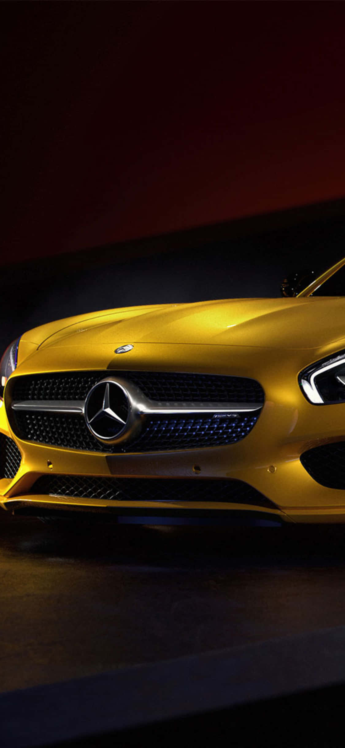 iPhone X AMG GT-R 背景 姜黃色 AMG GT 壁紙 — 一輛閃亮的金色梅賽德斯跑車在深紅色和黑色背景下從下方戲劇性地照亮。