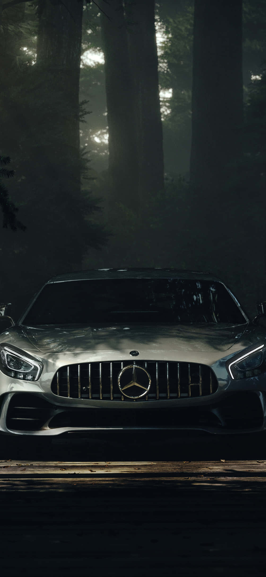 iPhone X AMG GT-R 背景 AMG GT 伴日光射線 壁紙 — 一架時尚的銀色 Mercedes-AMG GT 停泊在森林小徑上，周圍有霧氣繚繞的樹木，斑駁的光線穿過樹冠灑落。