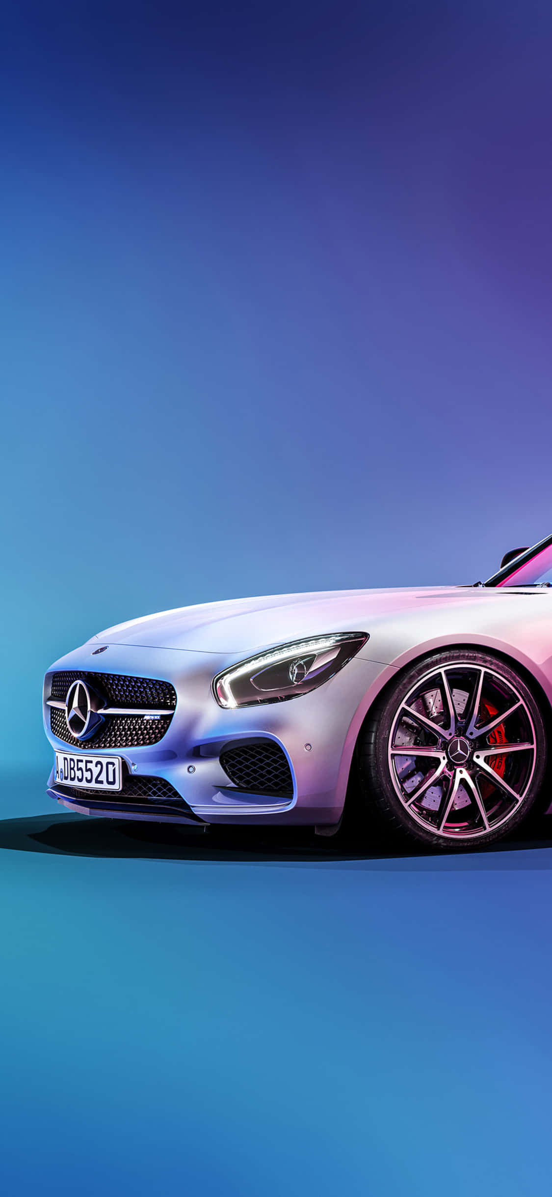 iPhone X AMG GT-R 背景銀色車頭 AMG GT 壁紙 — 一輛時尚的銀色 Mercedes-AMG GT 跑車在充滿活力的藍色和紫色工作室燈光下閃耀。
