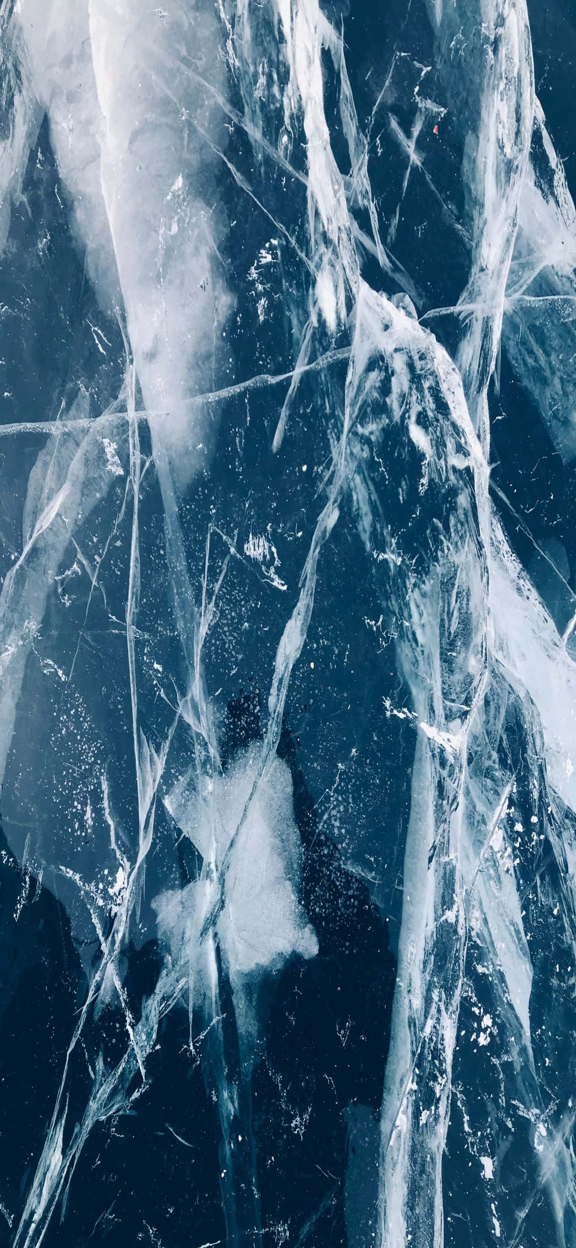 海洋藍 iPhone X 大理石背景 壁紙 — 深藍色冰凍湖面上複雜冰裂紋和冰凍紋理的近距離特寫。