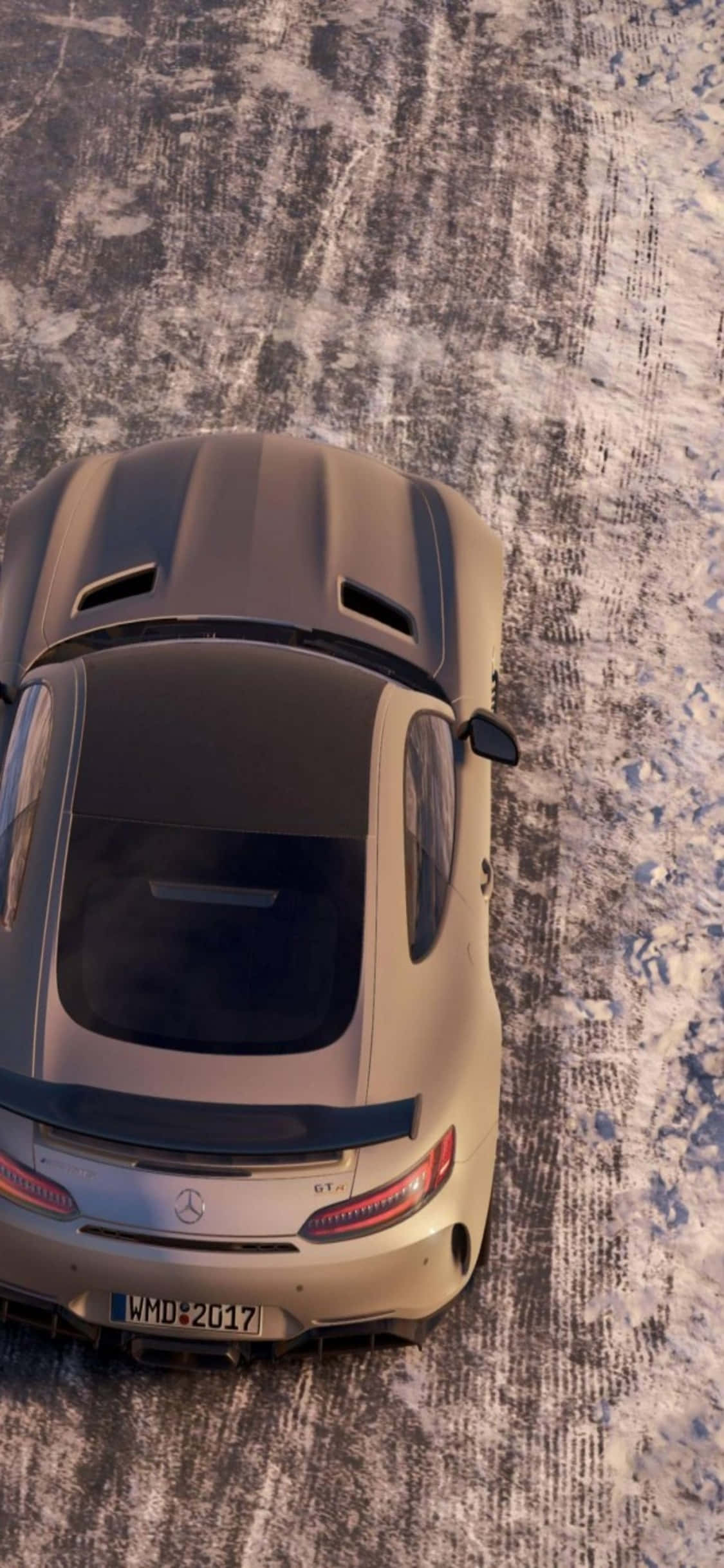 iPhone X《Project Cars》棕色跑車背景 壁紙 — 一架米色 Mercedes-AMG GT 停泊在帶有輪胎痕跡的雪地紋理表面上的俯視圖。