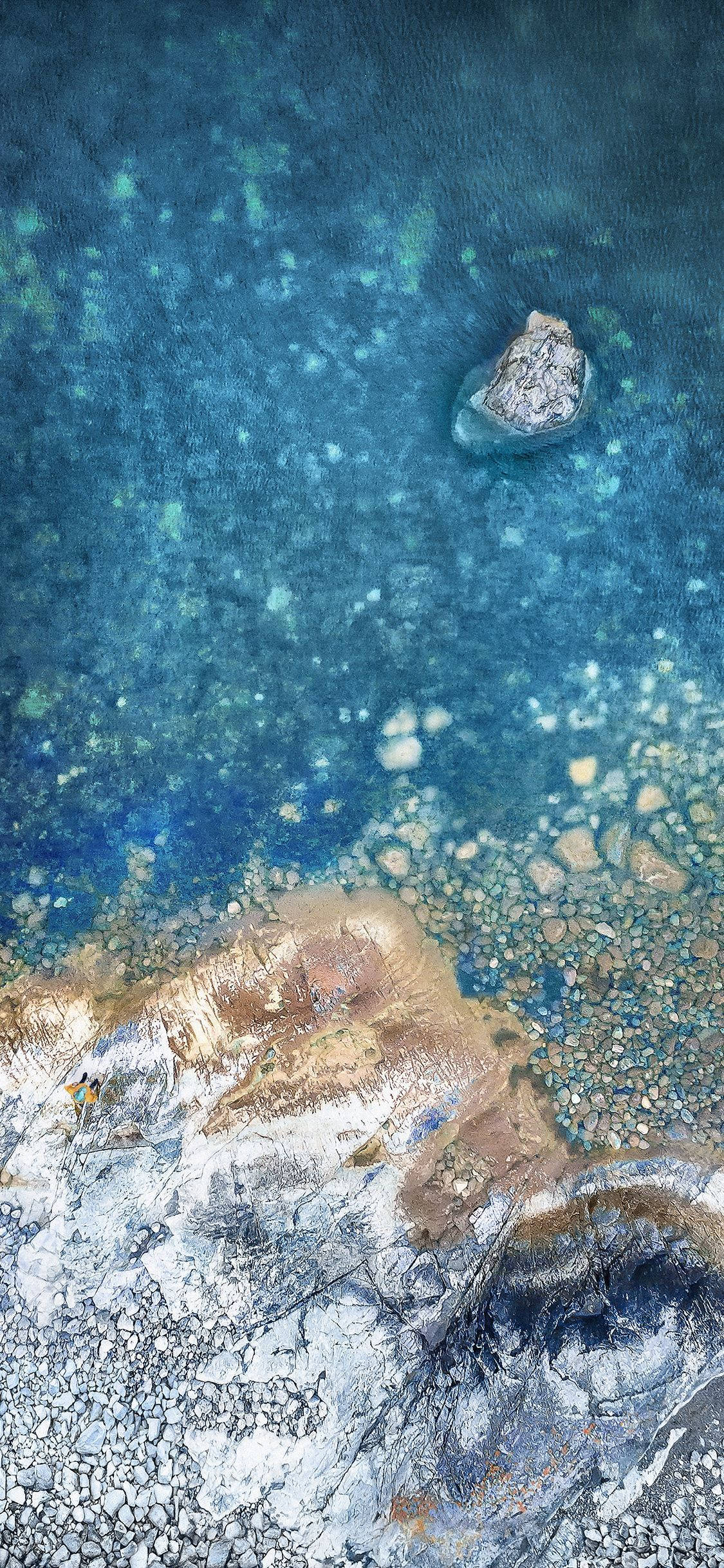 iPhone X原版岩石海岸 壁紙 — 從高空俯瞰，一塊孤立的岩石被清澈的碧綠海水環繞，下方是紋理分明的沙石海床。