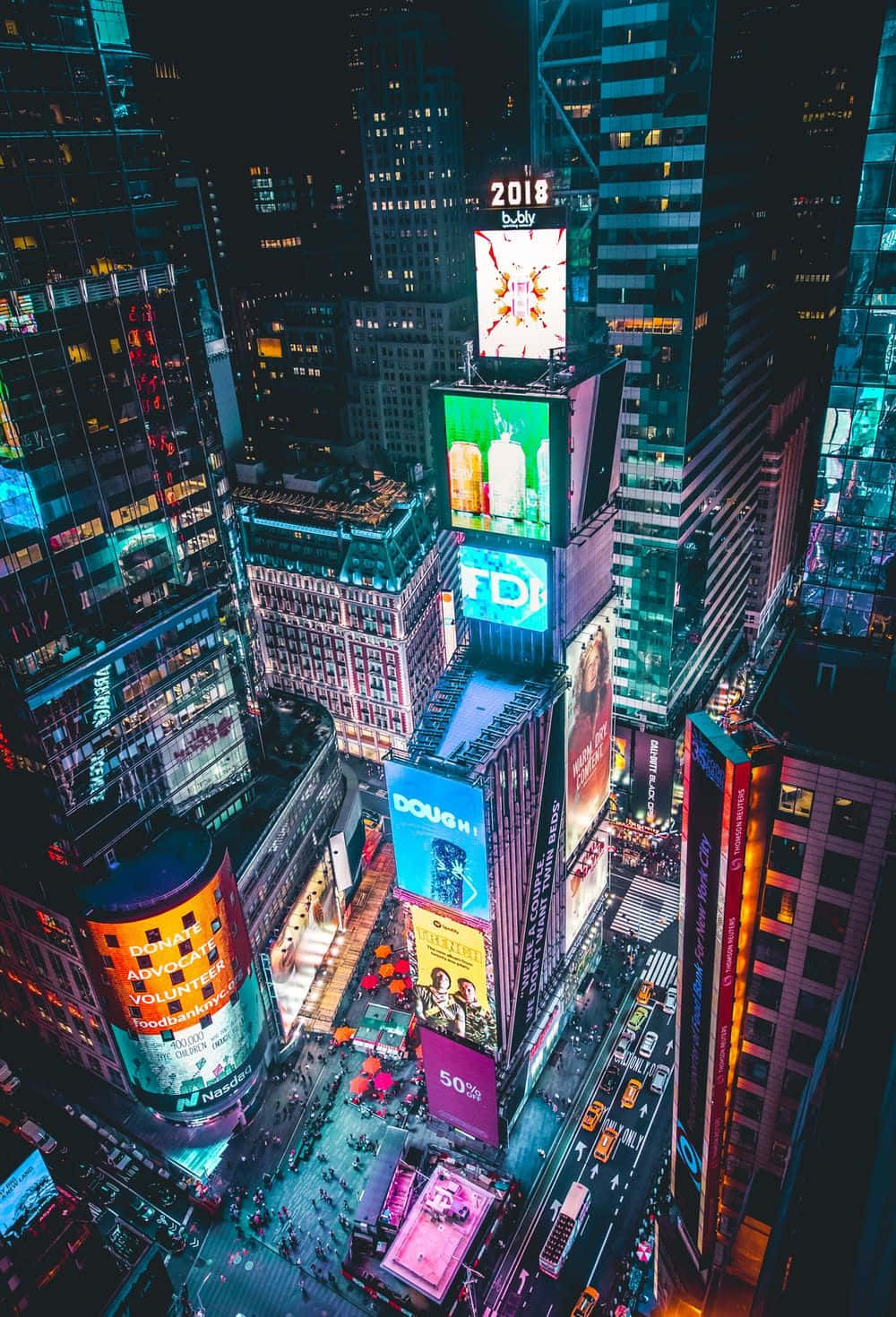 iPhone X拍攝的紐約夜景燈光 壁紙 — 夜晚時報廣場的鳥瞰圖，高聳的摩天大樓閃爍著鮮豔的數碼廣告牌，下方街道繁忙。