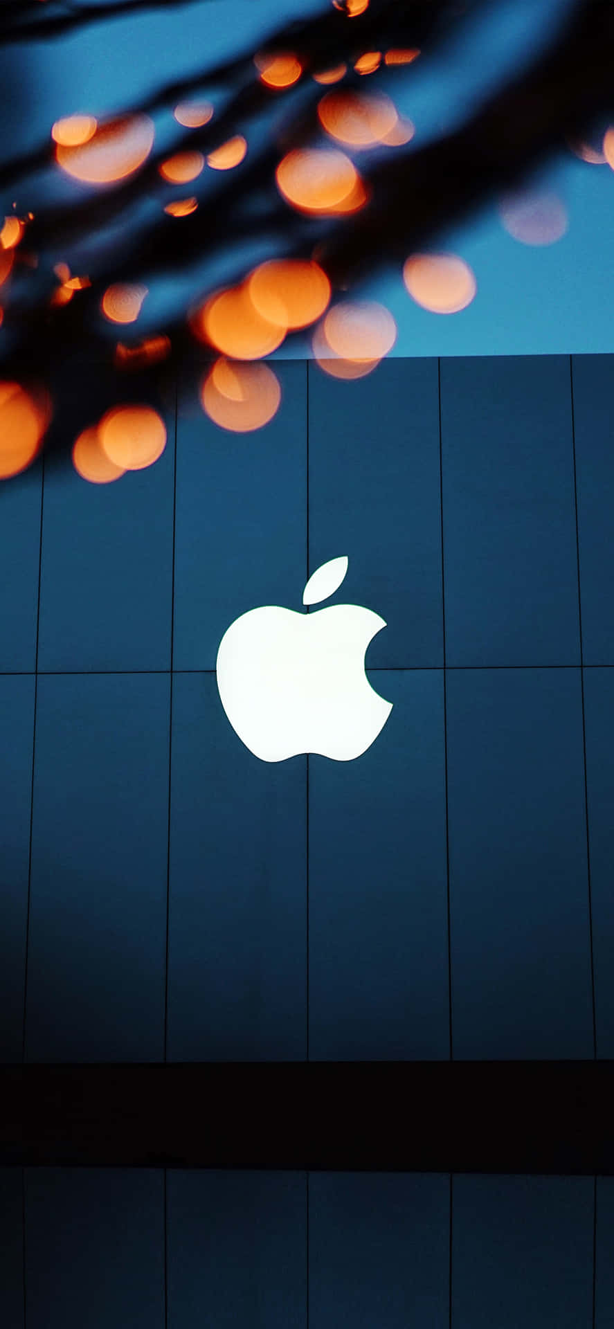 Apple標誌在藍色瓷磚牆上發光，上方有橙色燈光。