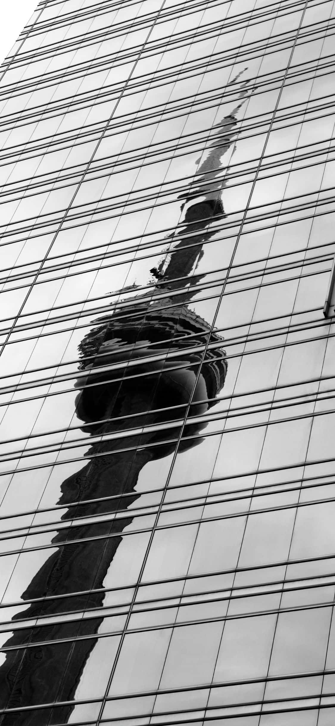 iPhone X 呈現西雅圖經典天際線 壁紙 — 現代摩天大樓玻璃外牆上捕捉到的 CN 塔黑白倒影，帶有網格線。