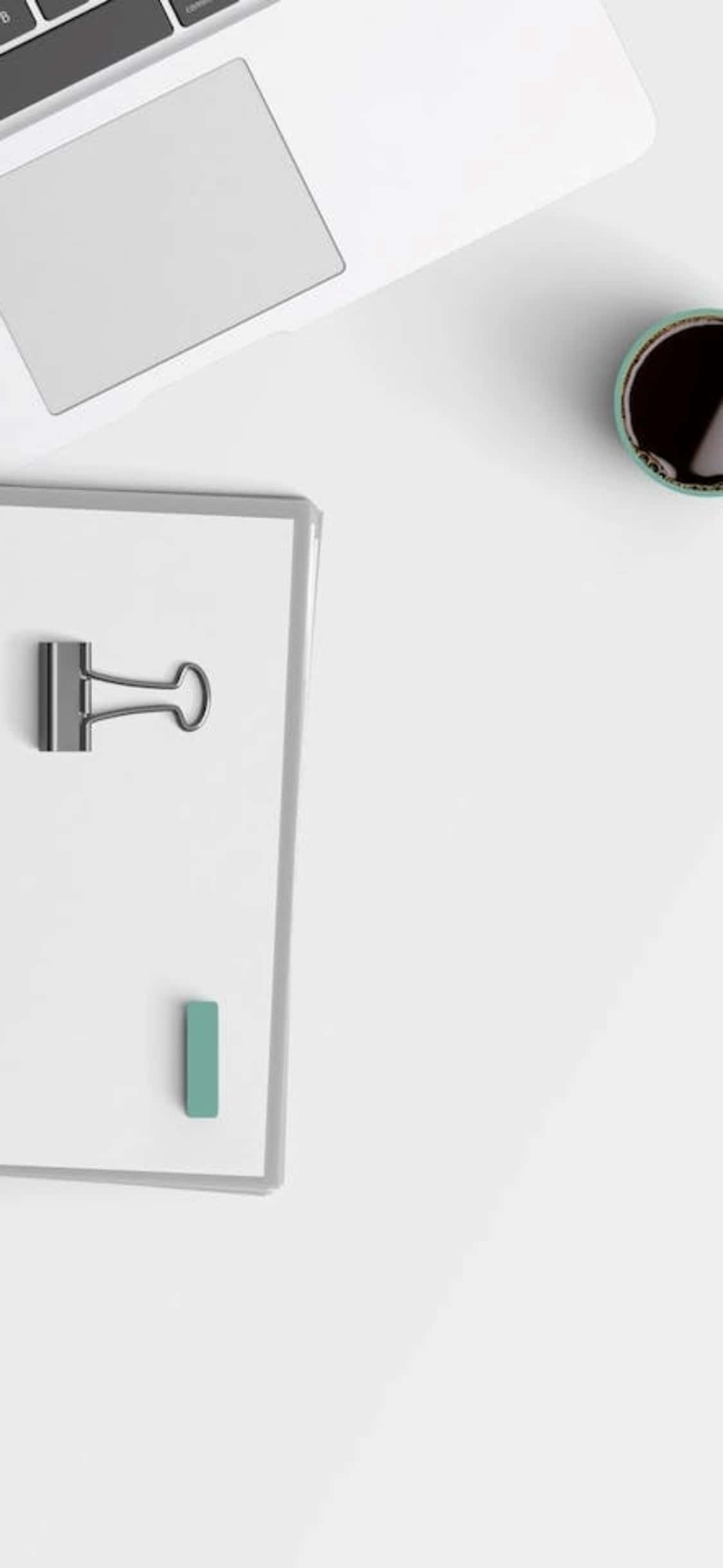 iPhone X 書桌背景：剪貼板與筆電 壁紙 — 白色書桌上放有手提電腦、筆記本、文件夾夾子和咖啡杯的簡約俯視圖。