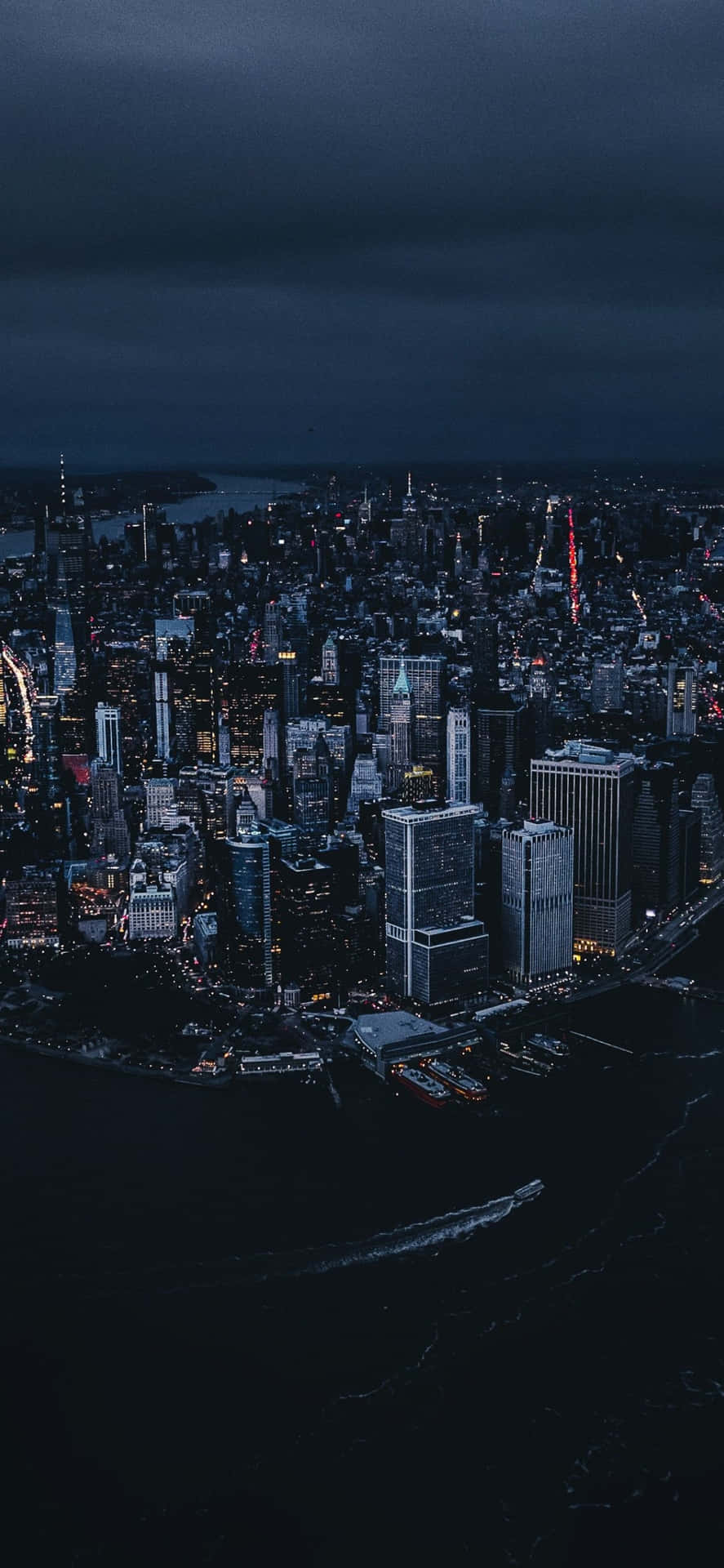 夜間城市景觀，燈火通明的建築物和下方的黑暗水域。