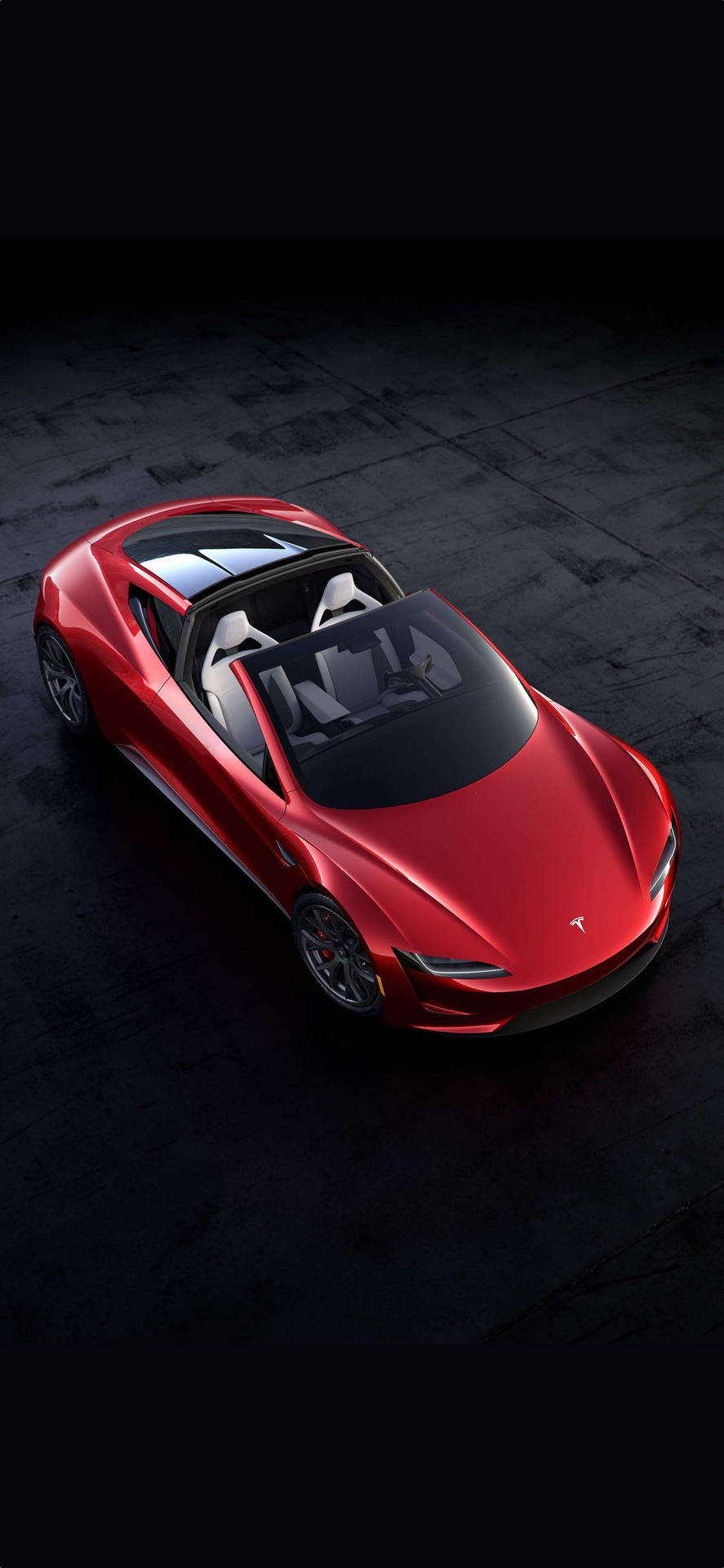 紅色Tesla Roadster開篷車，配備白色座椅，位於深色混凝土地板上。