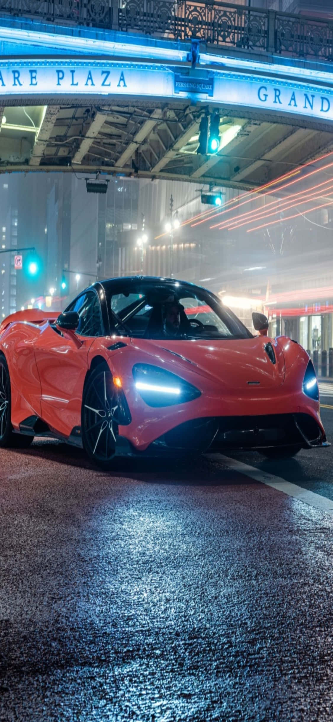 iPhone X 麥拉倫 720S 車展背景 壁紙 — 一輛鮮紅色的McLaren跑車在夜晚潮濕的城市街道上，在霓虹燈下閃閃發光。