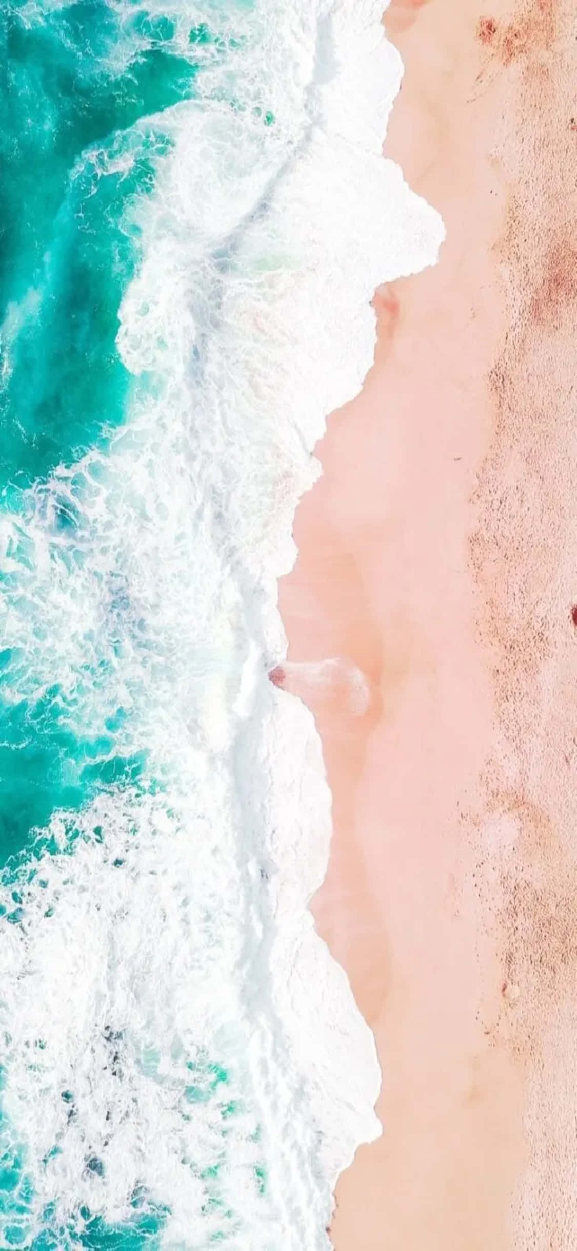 iPhone XS 海浪拍岸泡沫背景 壁紙 — 從上方俯瞰，藍綠色海浪拍打柔軟粉紅色沙灘的對角分割畫面。
