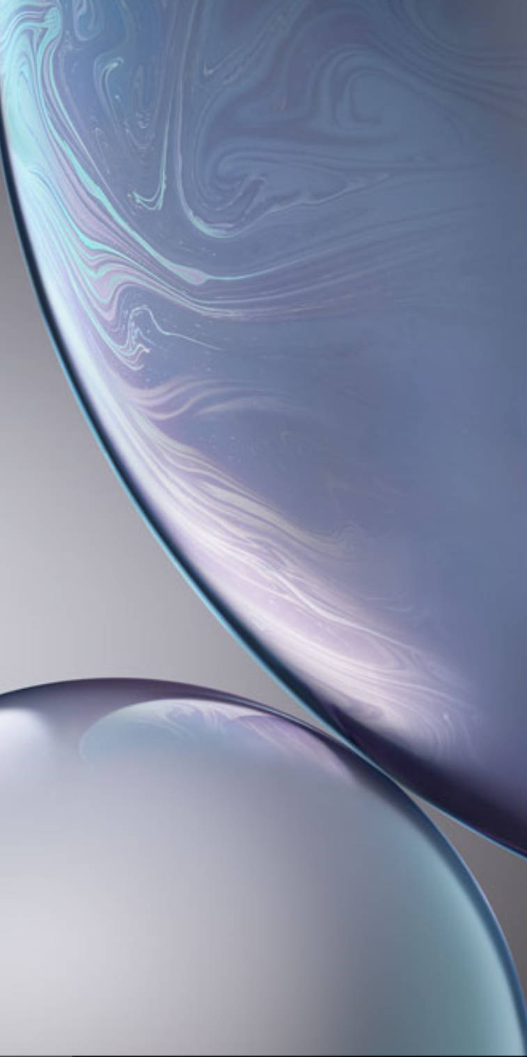 iPhone XS 柔和表面 壁紙 — 兩個半透明玻璃球體，帶有旋轉的彩虹色圖案，漂浮在柔和的灰色背景上。