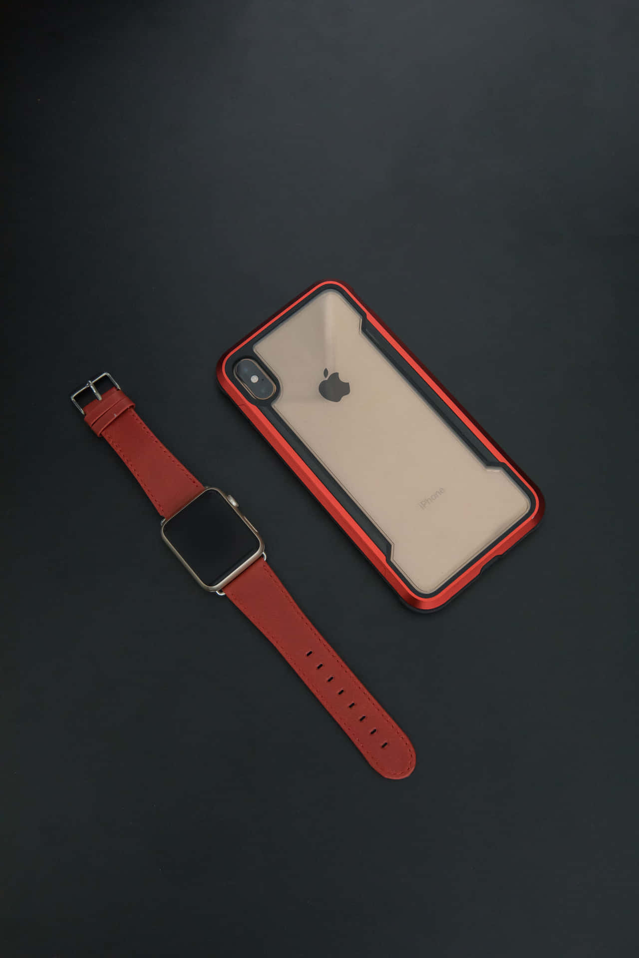 深色背景上的紅色皮革 Apple Watch 和 iPhone 保護殼。