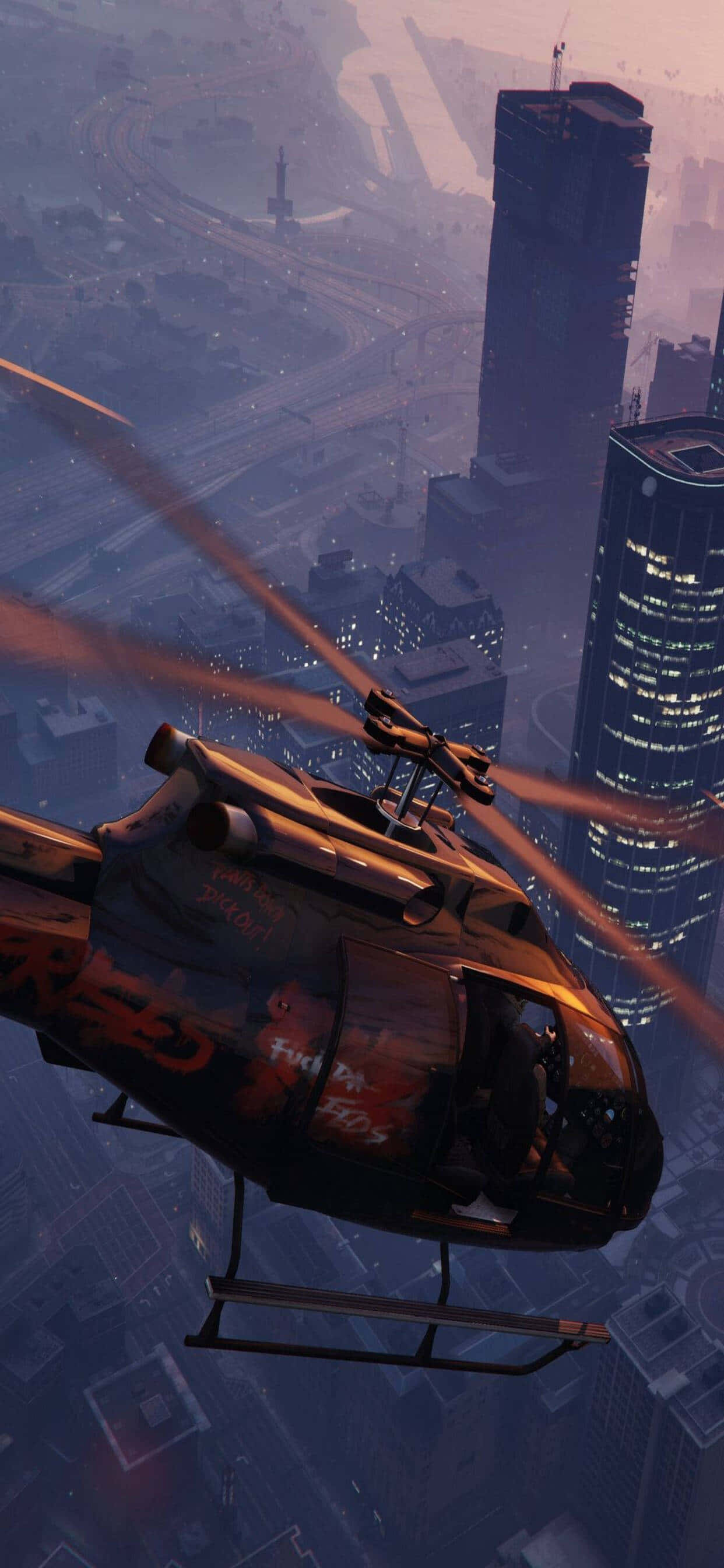iPhone XS Max《GTA V》直升機飛行場景 壁紙 — 一架帶有塗鴉的黑色直升機在黃昏時低飛過廣闊的城市天際線，下方是發光的摩天大樓。