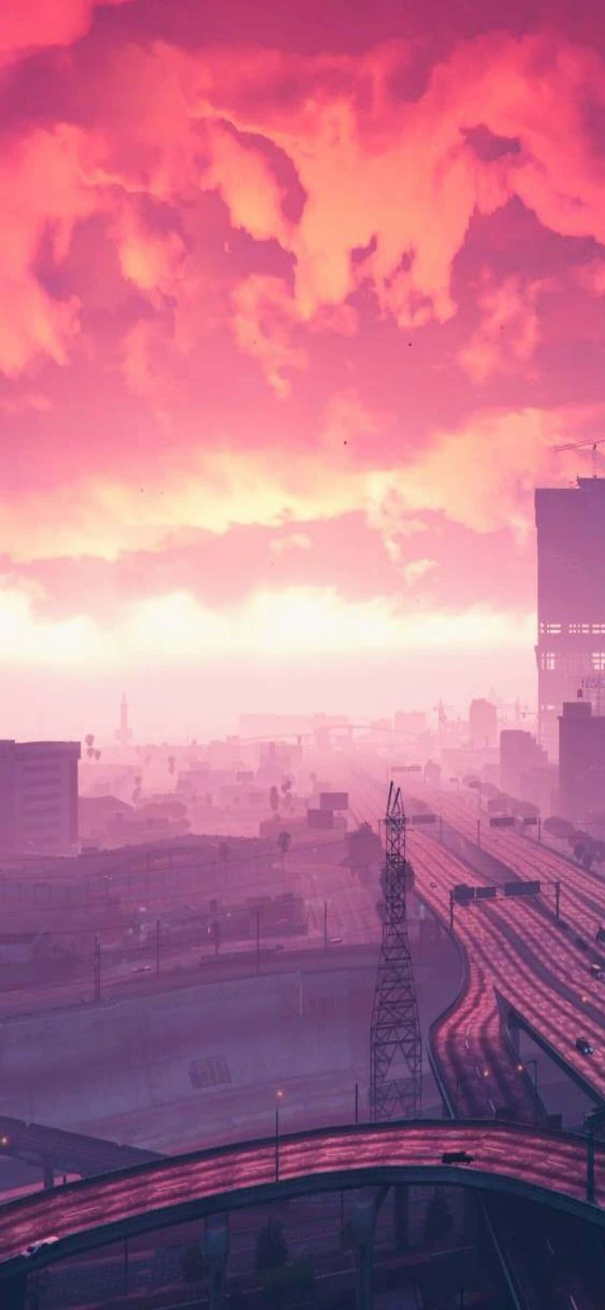 iPhone XS Max《GTA V》紫色夕陽背景 壁紙 — 日落時分的城市景觀，充滿活力的粉紅色和橙色雲彩籠罩在朦朧的城市天際線和發光的高速公路上方。