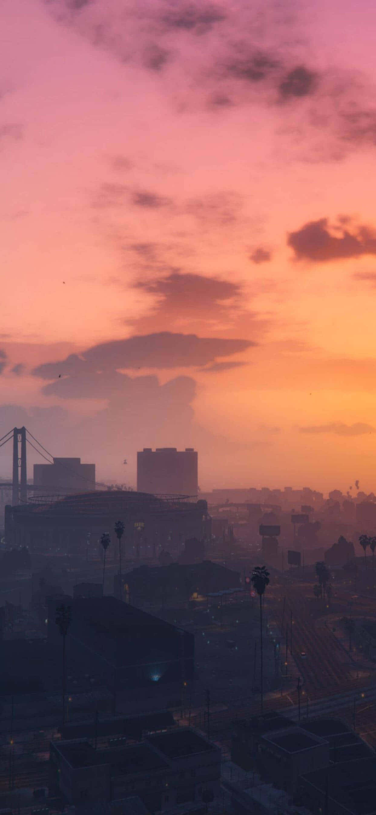 iPhone XS Max《GTA V》日落場景壁紙 壁紙 — 日落時分的城市景觀，溫暖的橙色和粉紅色天空在剪影建築物和遠處橋樑上投下柔和的光芒。