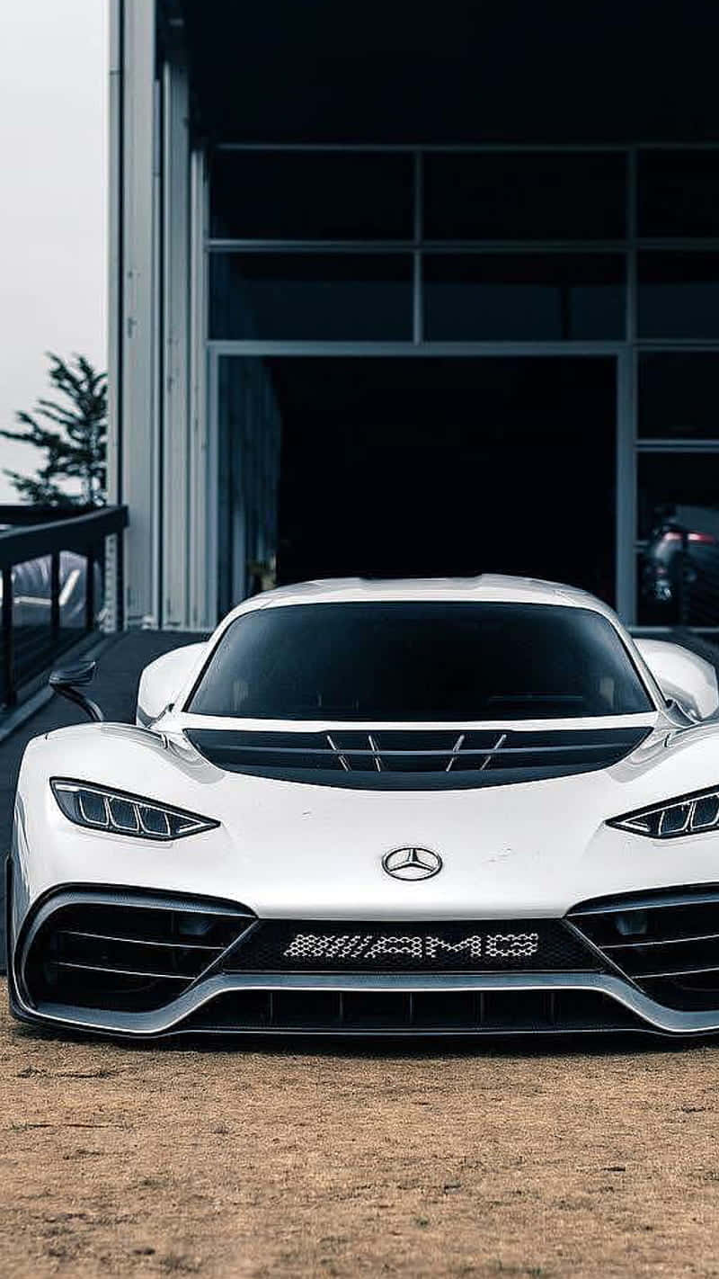 iPhone XS Max《Project Cars 2》白色梅賽德斯-AMG 背景 壁紙 — 一架時尚的白色梅賽德斯-AMG跑車停泊在泥土上，前面是現代玻璃車庫門。