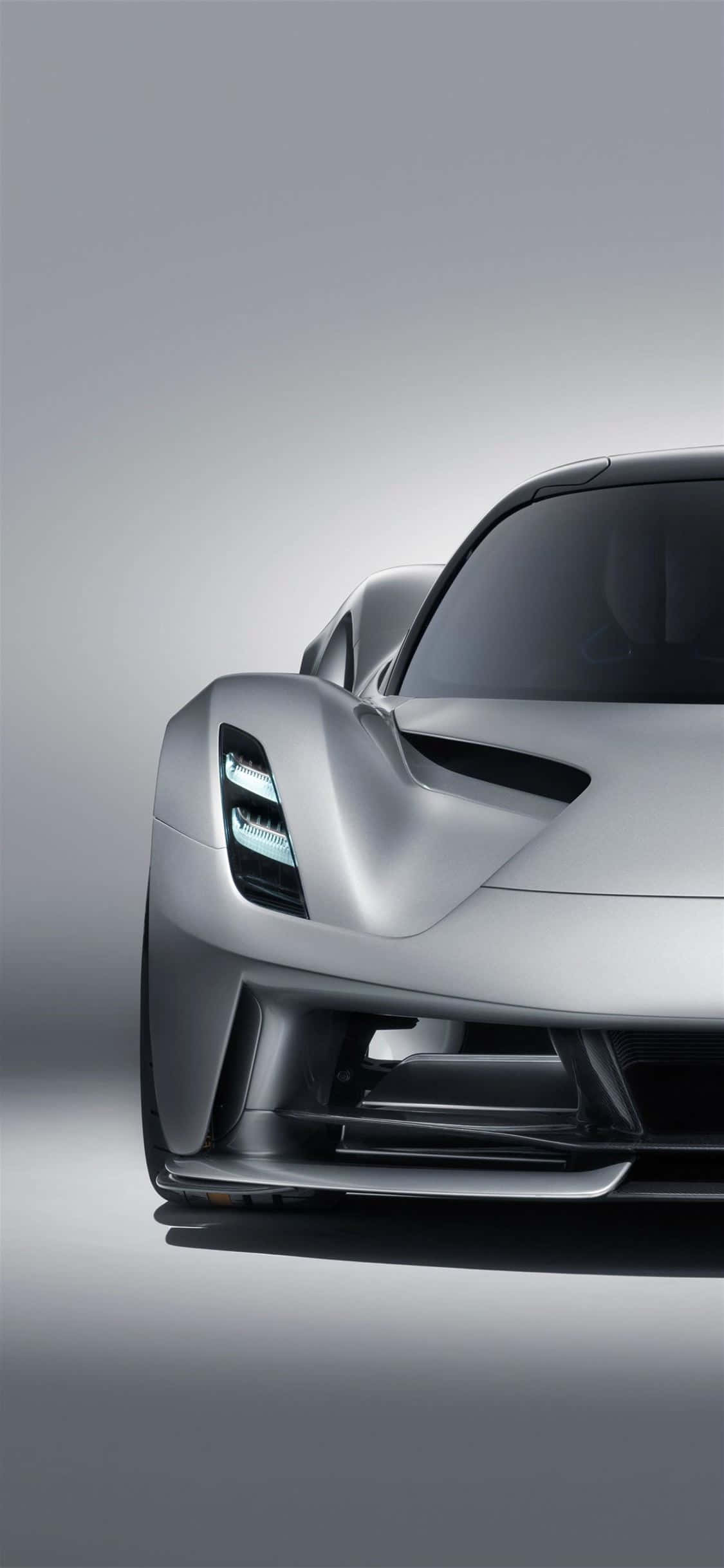 iPhone XS Max Project Cars 2 銀色 Aspark Owl 背景 壁紙 — 一輛線條銳利、車頭燈閃爍的時尚銀色跑車，在簡約灰色工作室背景前展示。