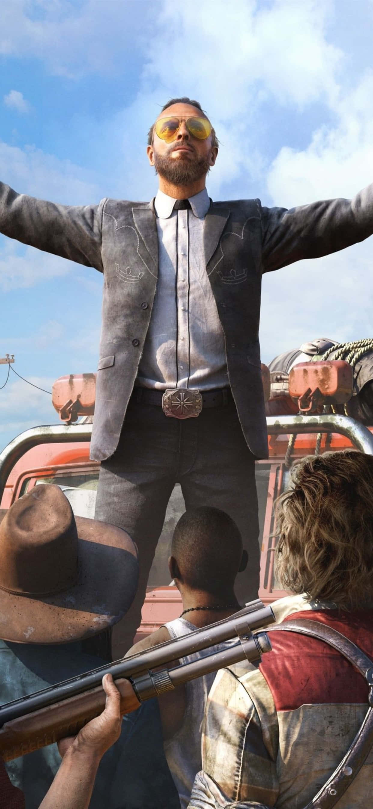iPhone Xs Max 上體驗《Far Cry 5》 壁紙 — 一名身穿灰色西裝和黃色太陽眼鏡的男子，在明亮的藍天下，雙臂張開，勝利地站在一輛紅色車輛上。