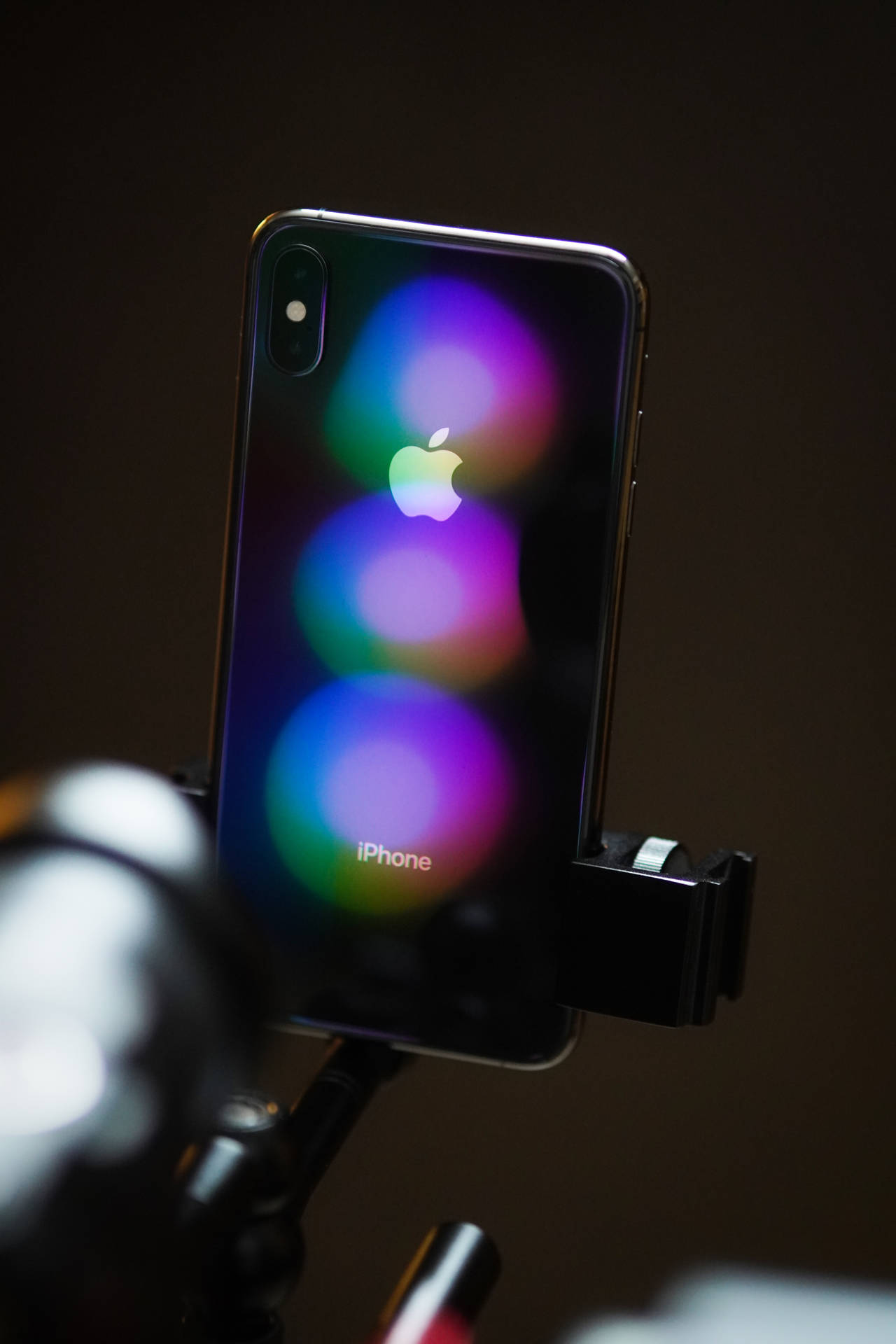 iPhone X，背景有彩色模糊燈光，安裝在三腳架上。