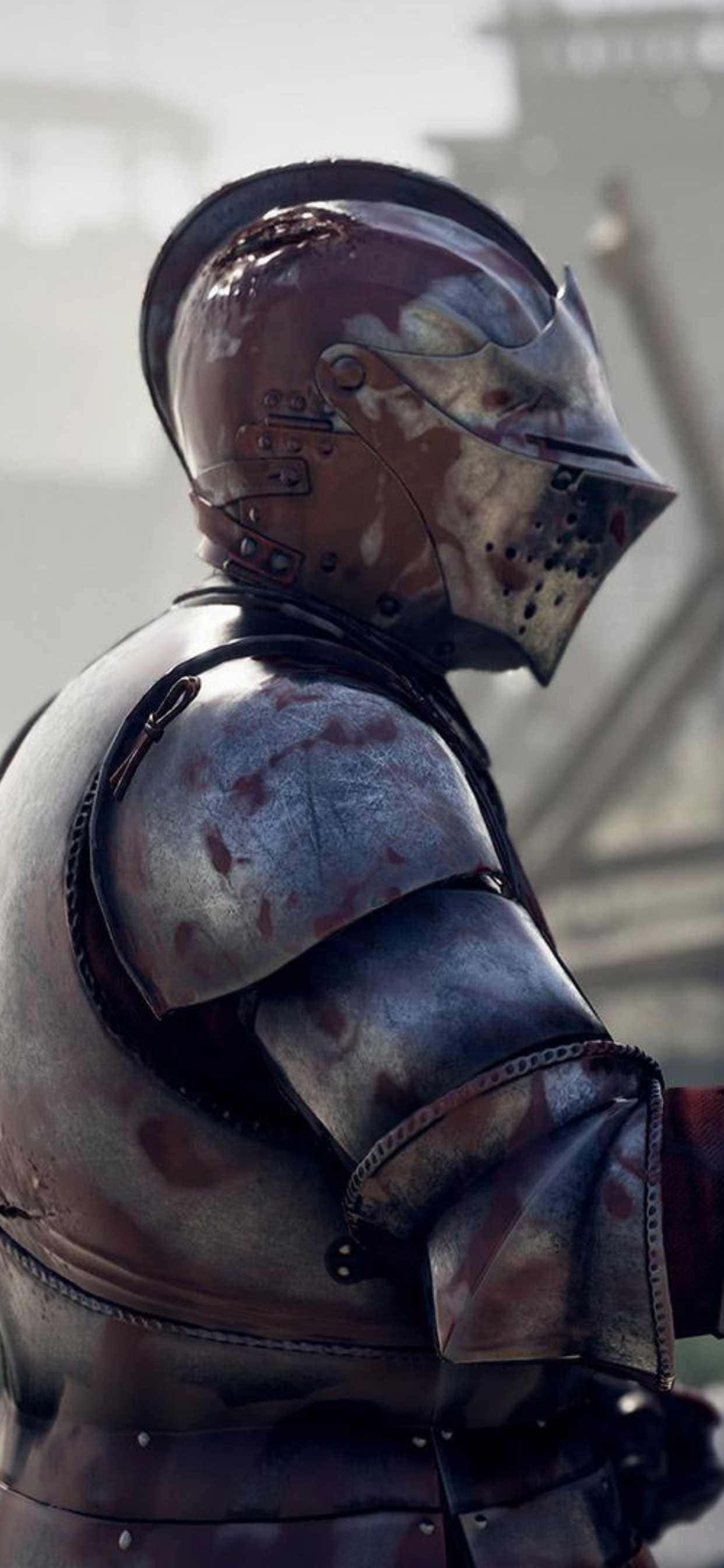 iPhone XS Max 展示《Mordhau》遊戲的庫存照片 壁紙 — 一個經歷風霜的中世紀騎士特寫，身穿佈滿戰鬥傷痕的板甲，帶有血跡和嚴峻的表情。