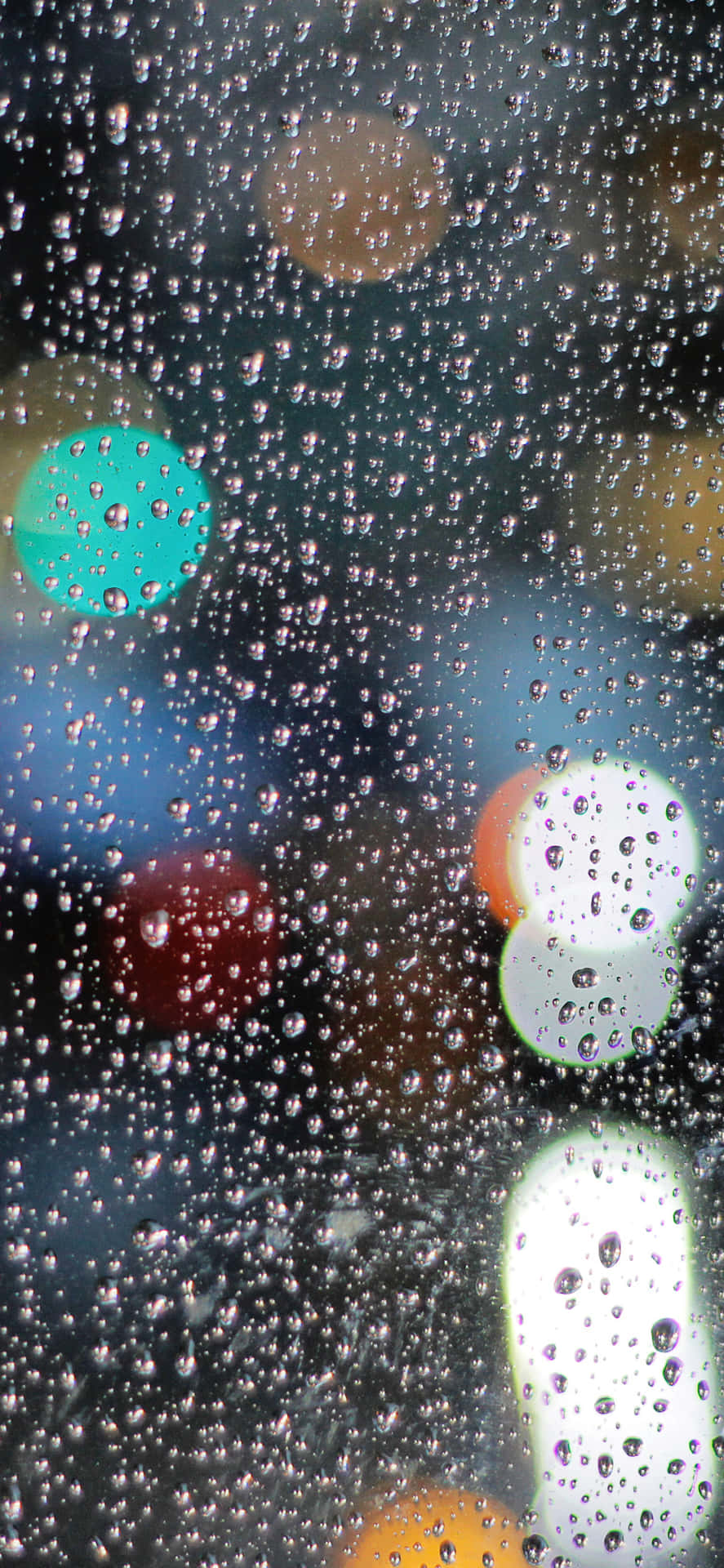 玻璃上的雨滴，背後是模糊多彩的城市燈光。