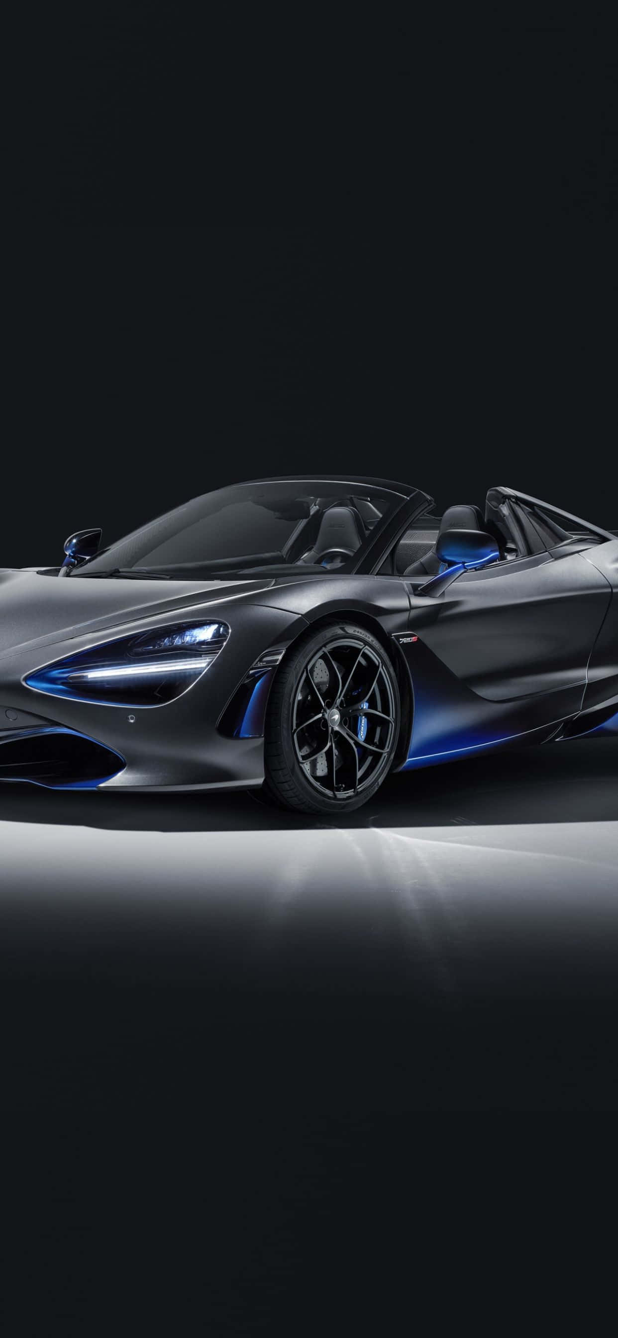 iPhone XS Max 與 McLaren 720S 背景 — Spider Zenith 黑色 壁紙 — 一輛時尚的啞光灰色McLaren 720S Spider，帶有發光的藍色飾邊和頭燈，在黑暗的攝影棚背景下照亮。