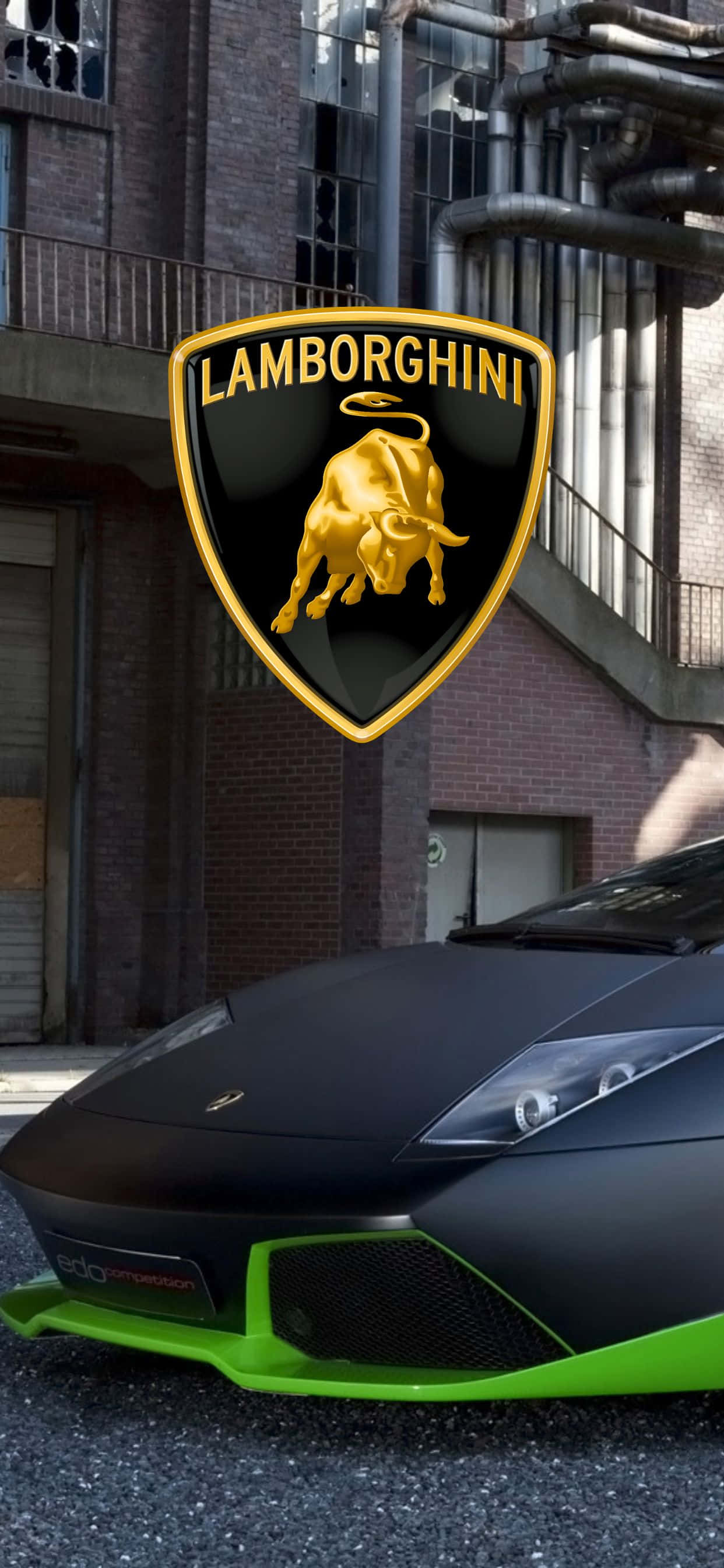 iPhone XS Max 蘭博基尼 Murcielago 背景 壁紙 — 一輛啞光黑色林寶堅尼帶有螢光綠色點綴，停在一棟帶有大型金色公牛標誌的磚砌建築前。