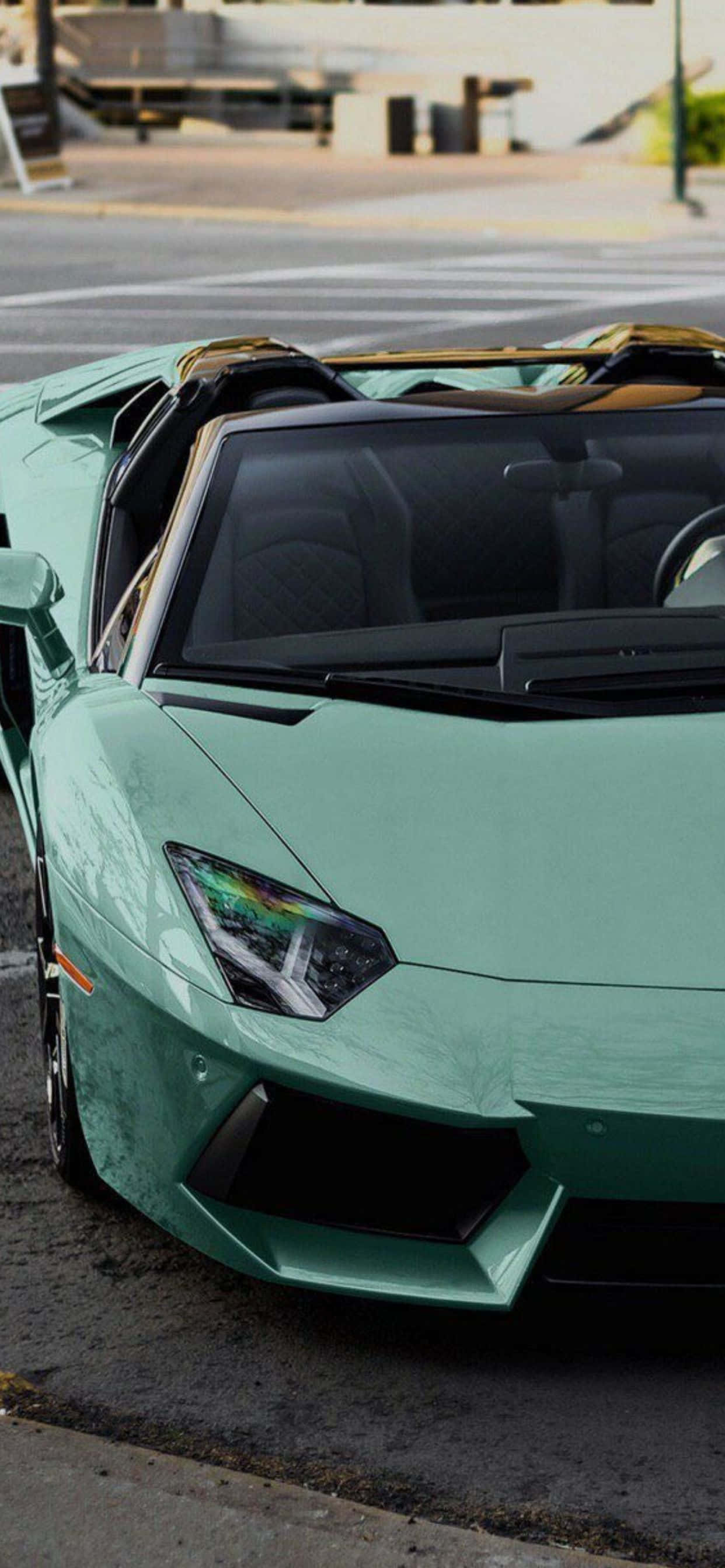 iPhone XS Max 蘭博基尼淺藍色背景 壁紙 — 一輛薄荷綠色的林寶堅尼 Aventador 開篷跑車停泊在城市的街道上，車頂敞開。