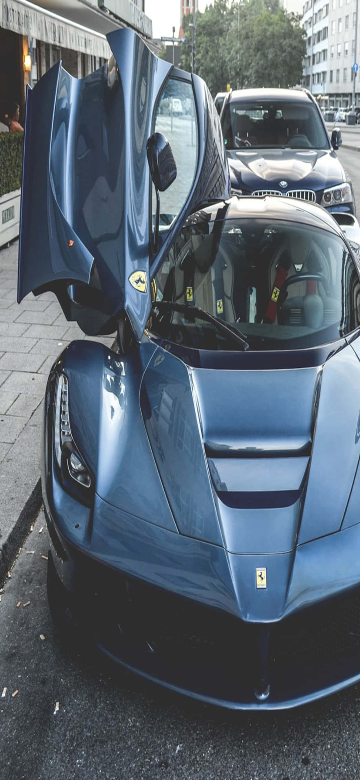iPhone XS Max 賽車背景：藍色敞篷 LaFerrari 壁紙 — 一架時尚的藍色法拉利LaFerrari，鷗翼門打開，停泊在城市的街道上。