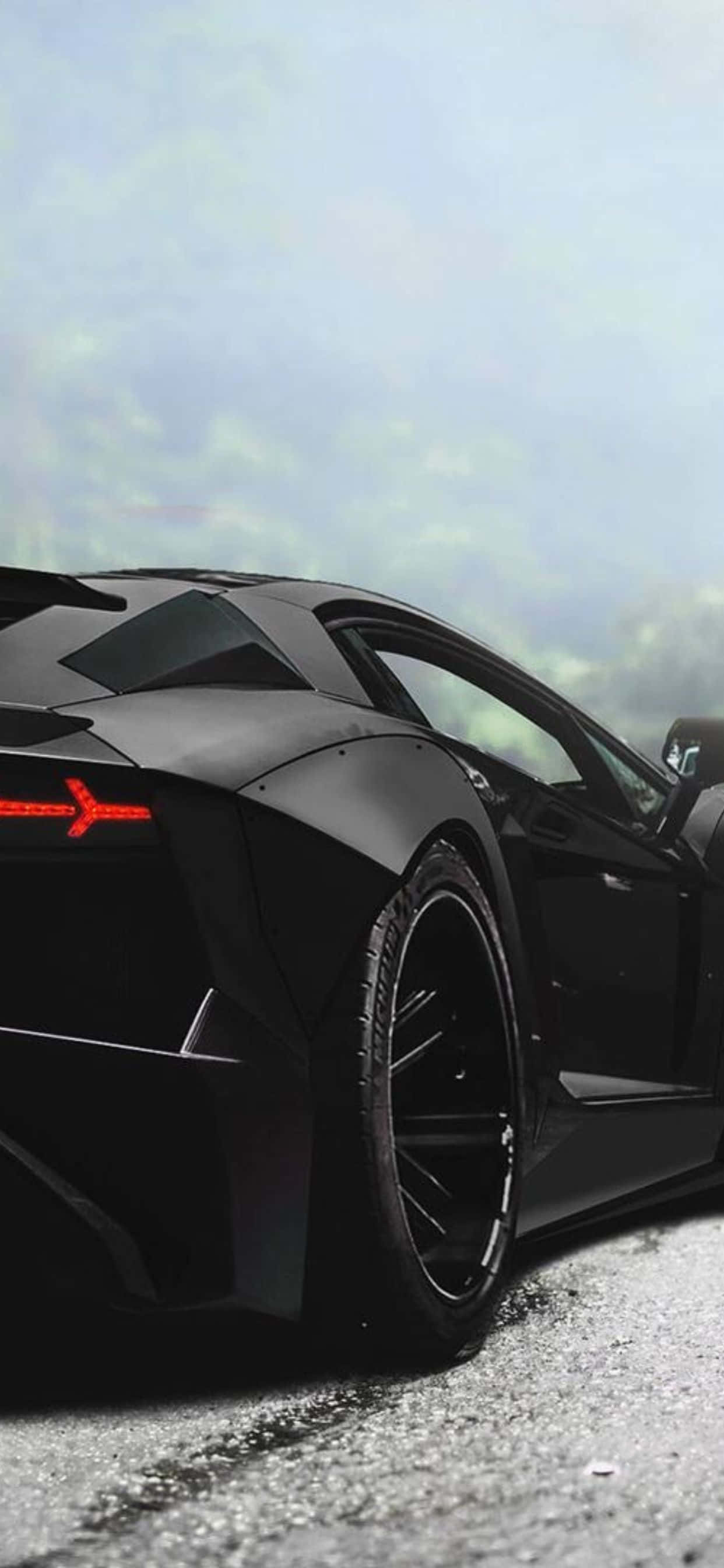 iPhone XS Max 黑色蘭博基尼Aventador 後視背景 壁紙 — 一架型格啞黑色林寶堅尼Aventador停泊在濕瀝青路上，背景是霧氣瀰漫的綠色山丘。