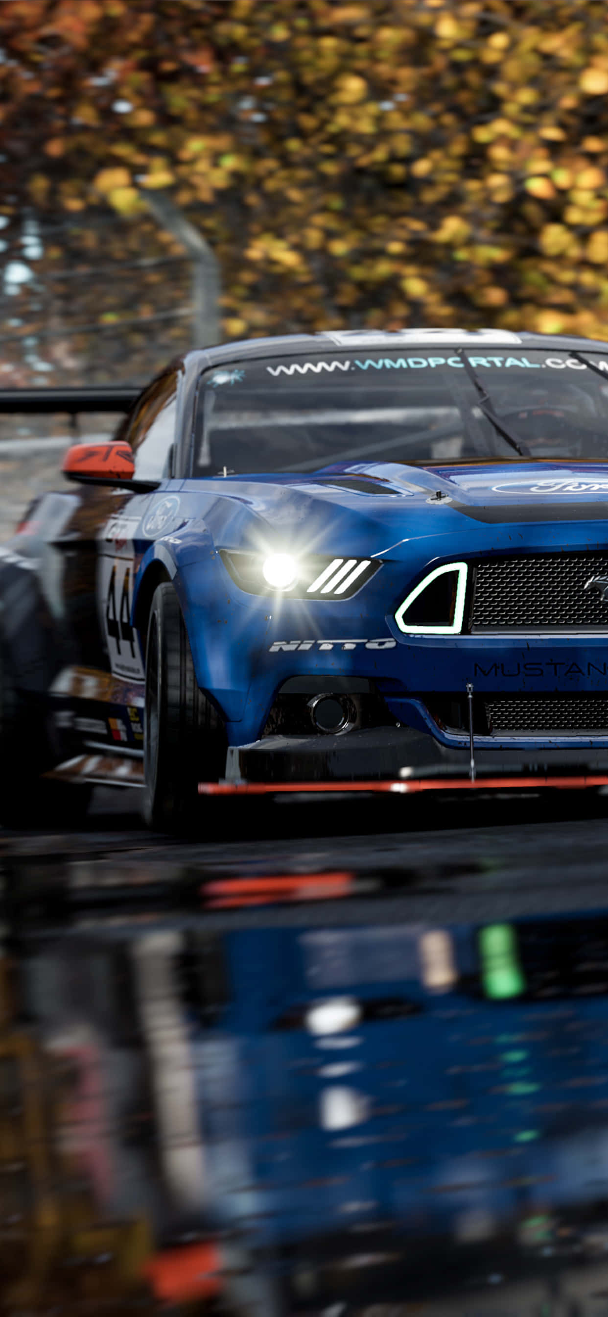 iPhone XS Max《Project Cars 2》藍色 2018 福特野馬背景 壁紙 — 一輛藍色賽車，編號44，在潮濕的秋日森林中疾馳，金色落葉倒映在水坑中。