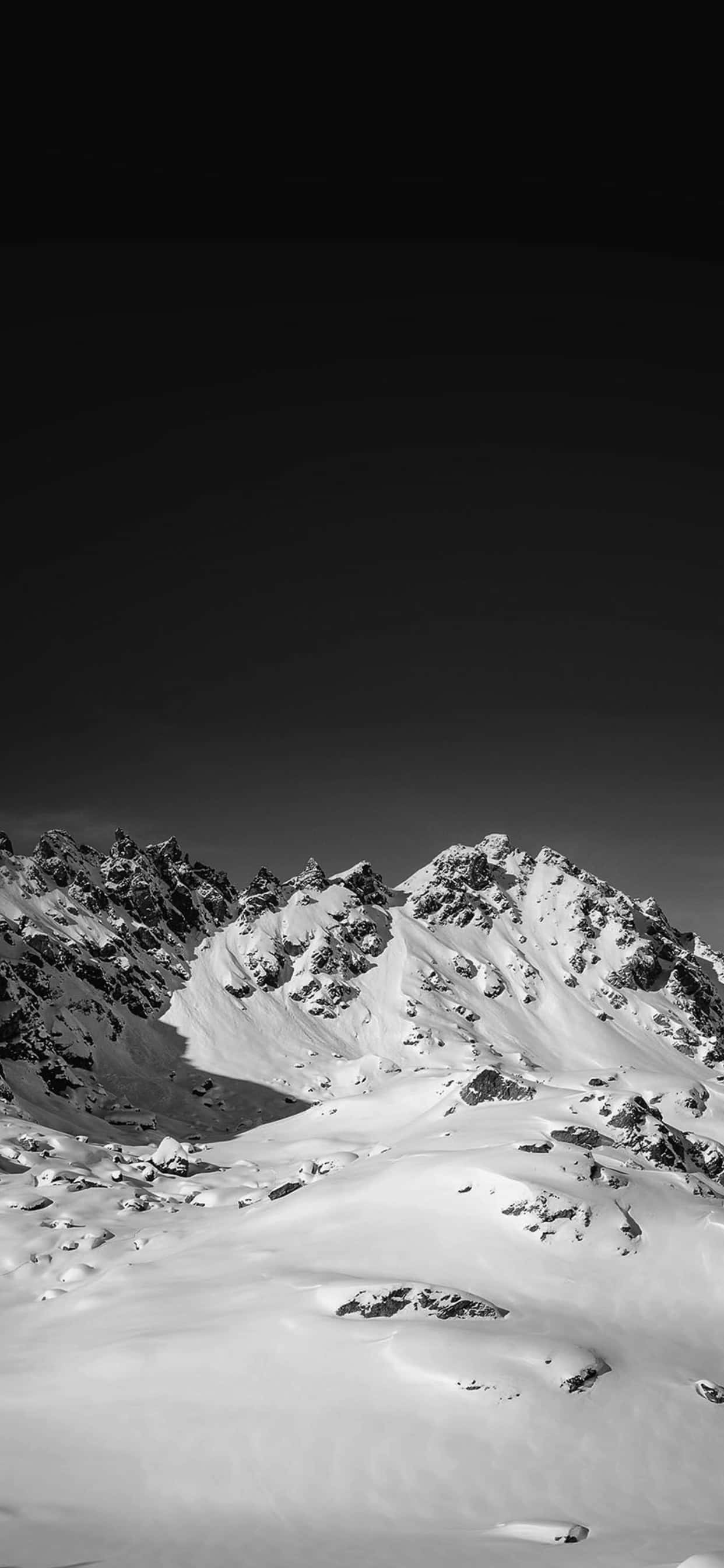iPhone XS Max冬季背景：黑白雪山 壁紙 — 在黑暗天空下，一個清晰的黑白山脈被雪覆蓋。