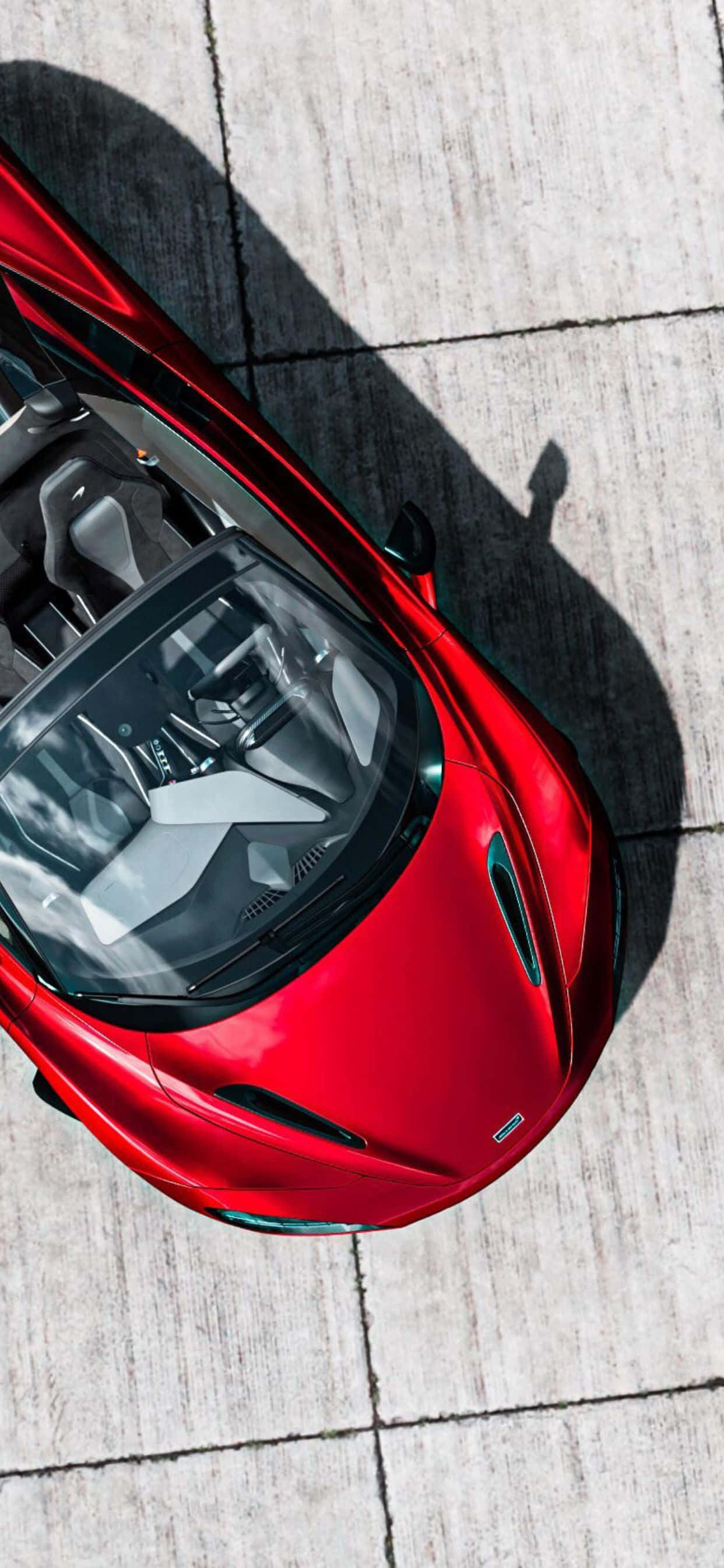 iPhone Xs Max與McLaren 720S：科技與速度的完美結合 壁紙 — 一輛鮮紅色、設計流線型的跑車停泊在淺灰色混凝土表面上，從正上方觀看。