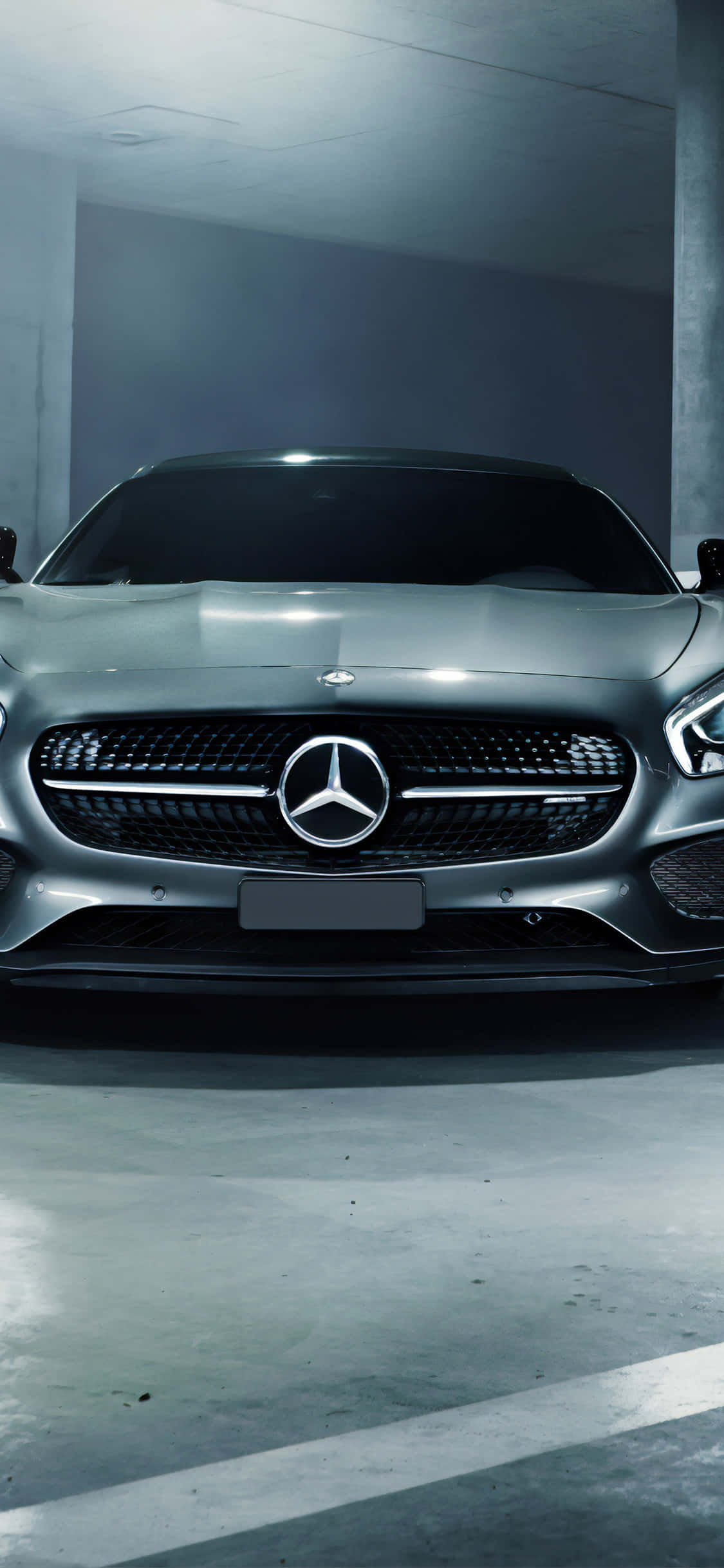 銀色 iPhone XS Mercedes AMG 停車場背景 壁紙 — 一架時尚的銀色 Mercedes 跑車在簡約的混凝土車庫中，在冰冷的人造燈光下閃閃發光。