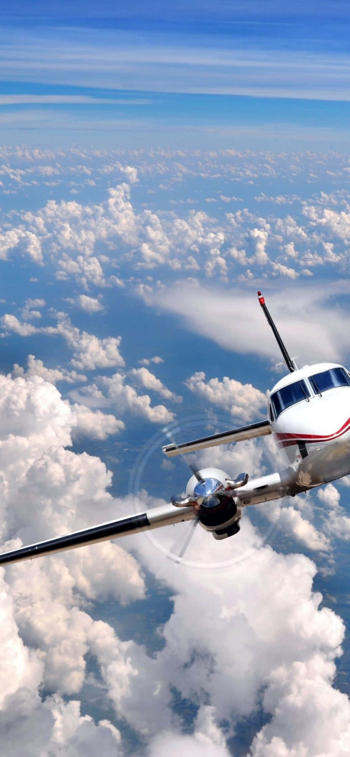 與 iPhone Xs 和 Microsoft Flight Simulator 一同展開精彩冒險 壁紙 — 一架小型螺旋槳飛機在晴朗藍天下翱翔於蓬鬆白雲之上。