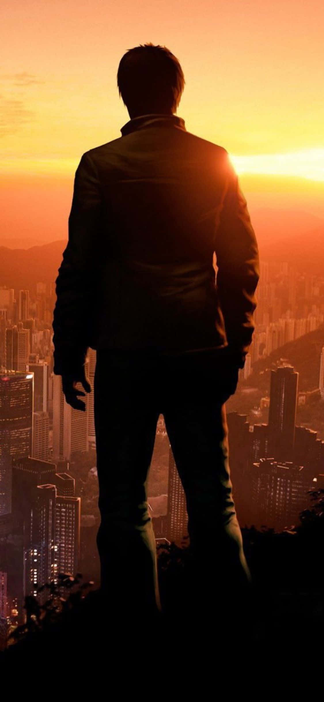iPhone XS《Sleeping Dogs》城市日落背景 壁紙 — 一個穿著西裝的男人的孤獨剪影站在山頂上，俯瞰著夕陽下溫暖橙色和黃色調的廣闊城市。