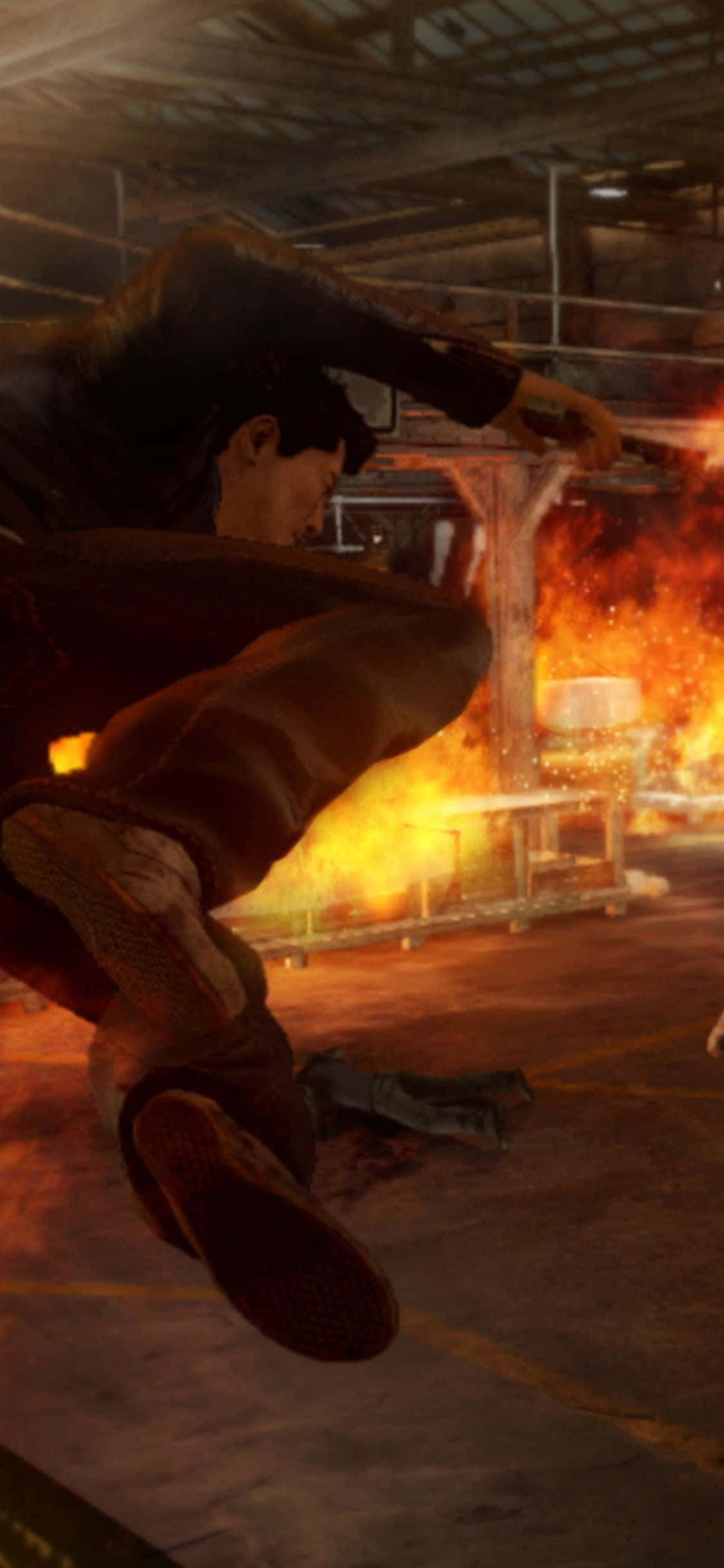 iPhone XS《Sleeping Dogs》「報復」任務倉庫跳躍背景 壁紙 — 一個男人在半空中向昏暗工業倉庫中熊熊燃燒的火焰踢去。