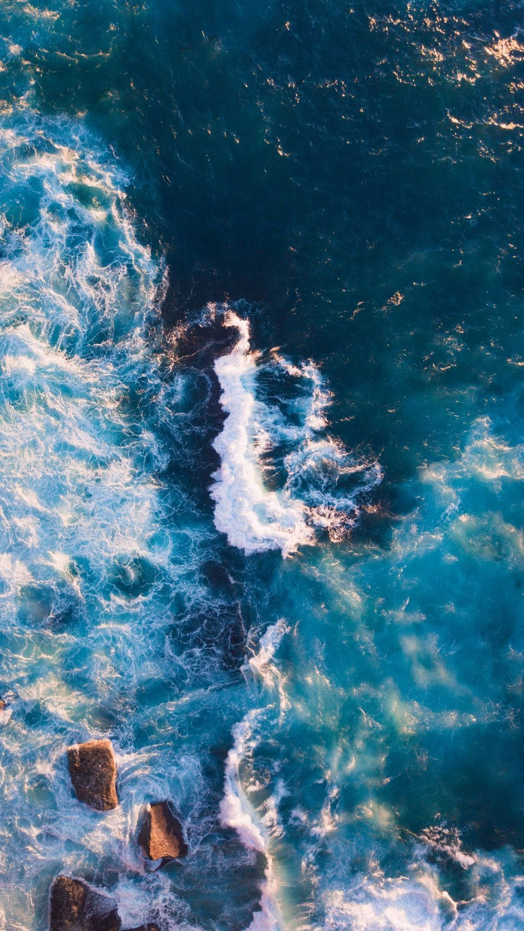 碧綠色的海浪從上方拍打深色岩石。
