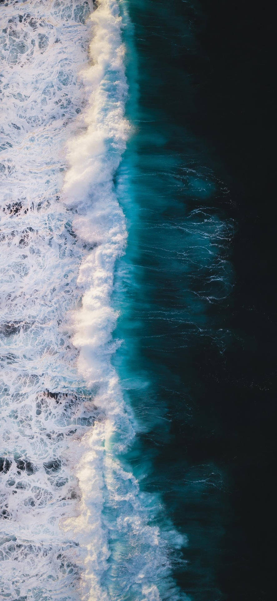 從高空拍攝的海浪撞擊，白色泡沫與深藍色海水形成對比。