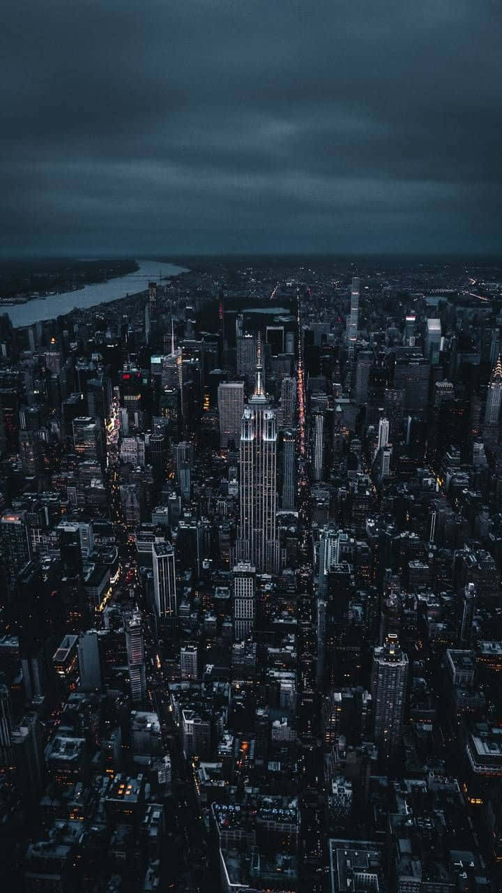 黃昏時分紐約市的鳥瞰圖，在黑暗多雲的天空下，摩天大樓燈火通明。