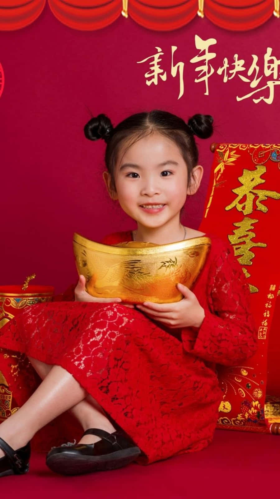 以精緻中國新年主題iPhone背景迎接新年 壁紙 — 一個穿著紅色傳統裙子的快樂小女孩，在帶有農曆新年裝飾的喜慶紅色背景前拿著金條。