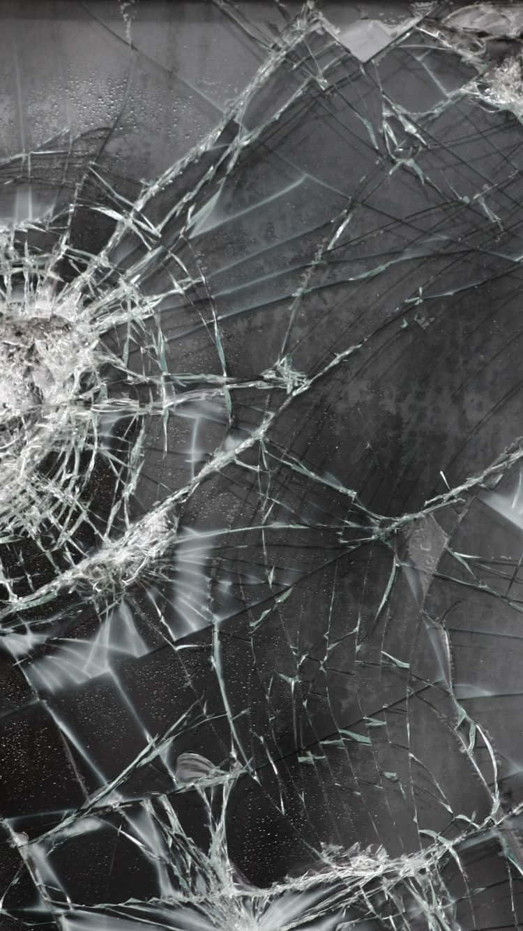 iPhone 屏幕破裂粉碎惡作劇 壁紙 — 一個破碎的玻璃表面，帶有複雜的裂紋和反光碎片，背景為深色。