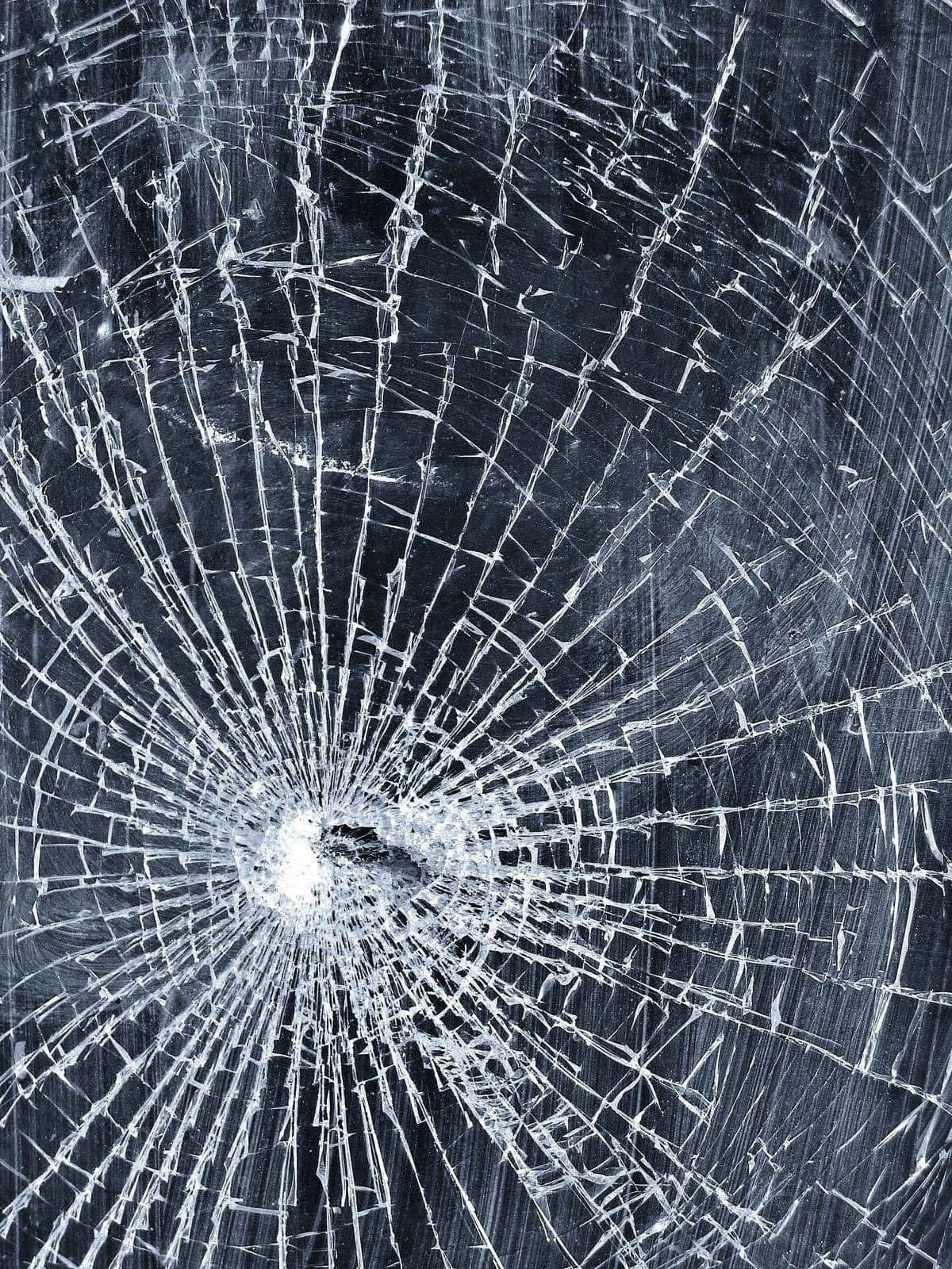 iPhone 屏幕裂痕惡作劇照片 壁紙 — 一塊破碎的玻璃表面，中央撞擊點在深色背景上散發出複雜的裂紋。