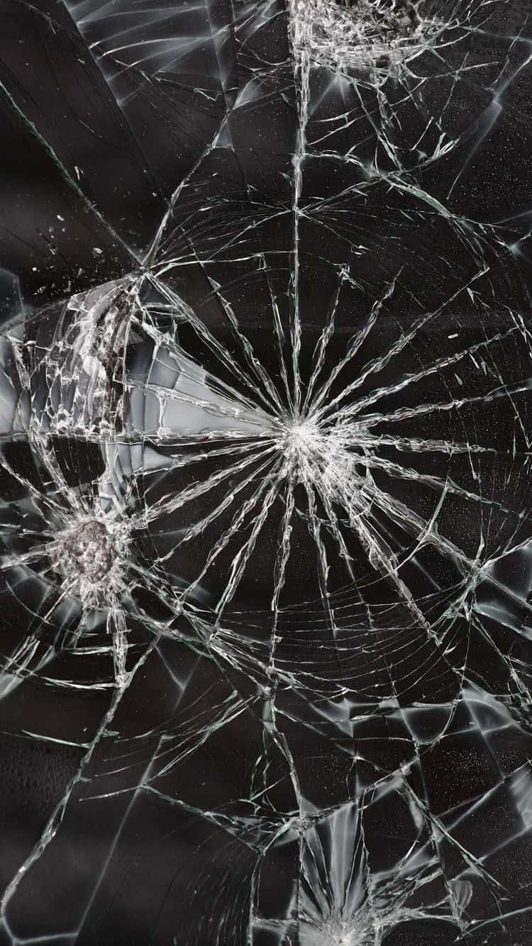 iPhone 屏幕裂縫欺騙式照片 壁紙 — 特寫鏡頭，顯示在深色背景下，從撞擊點向外輻射的複雜裂紋的破碎玻璃。